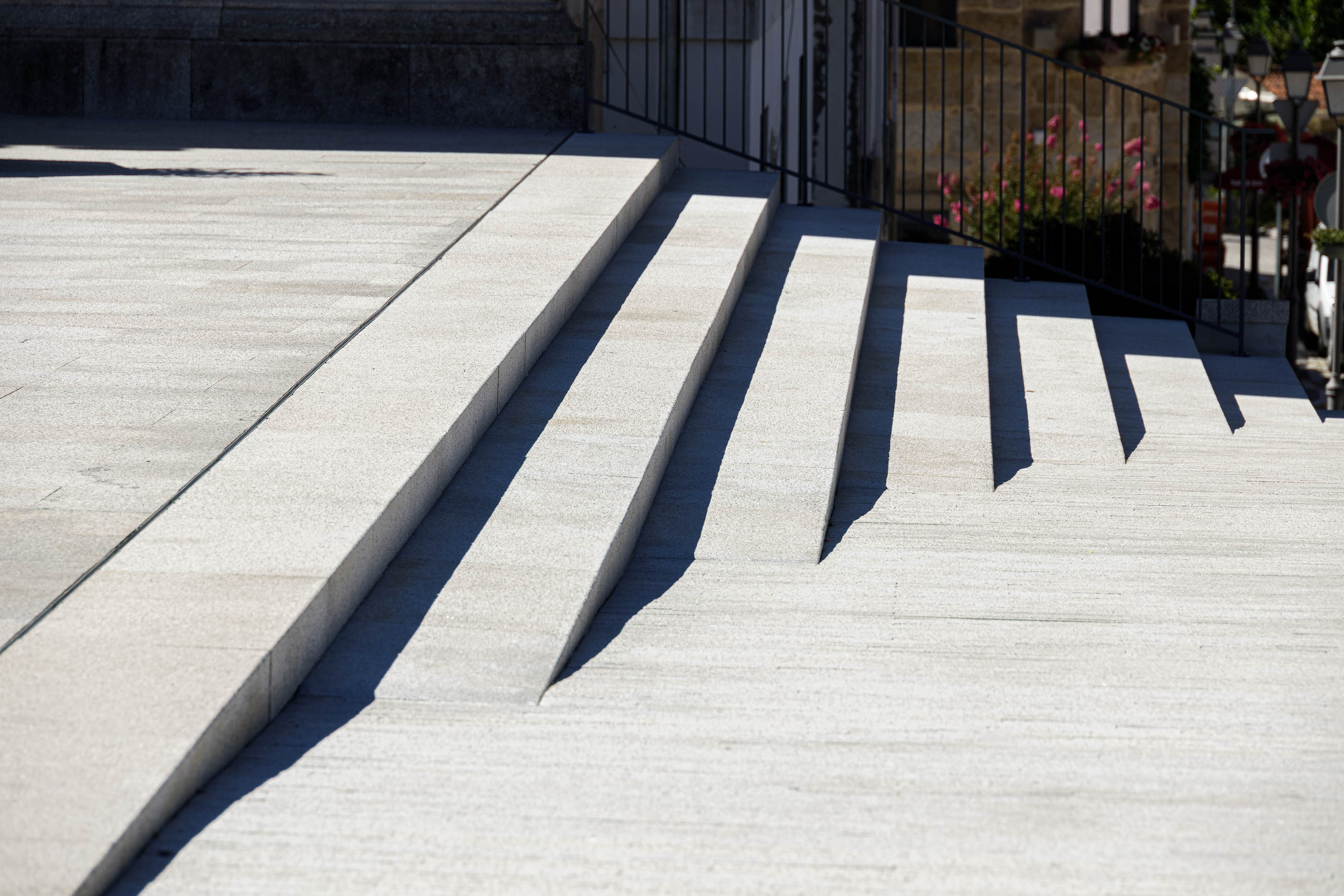 Praça: Escadaria em granito cinza claro com rampa de acesso e corrimão em ferro. — Requalificação da Praça do Município de Ribeira de Pena arquitetura AXR - Arquitetura e Design em Vila Real