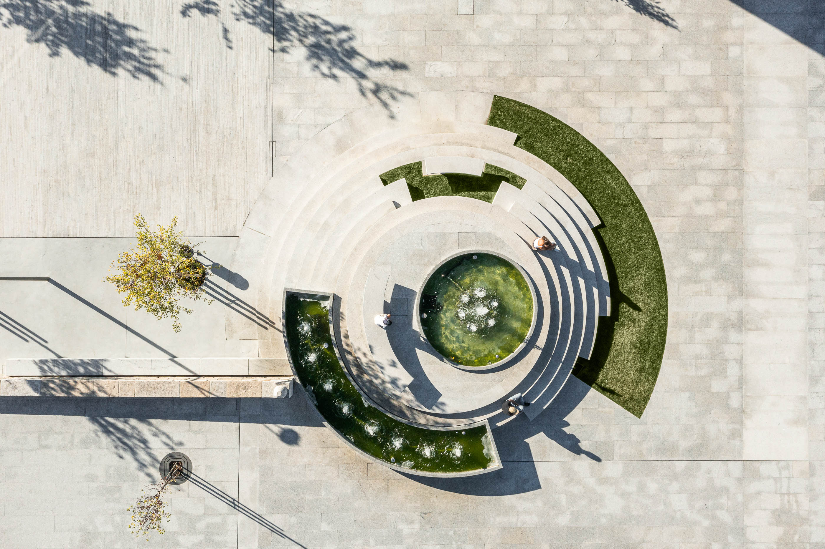Praça: Vista aérea da fonte escalonada com relvado e pessoas a relaxar. — Requalificação da Praça do Município de Ribeira de Pena arquitetura AXR - Arquitetura e Design em Vila Real