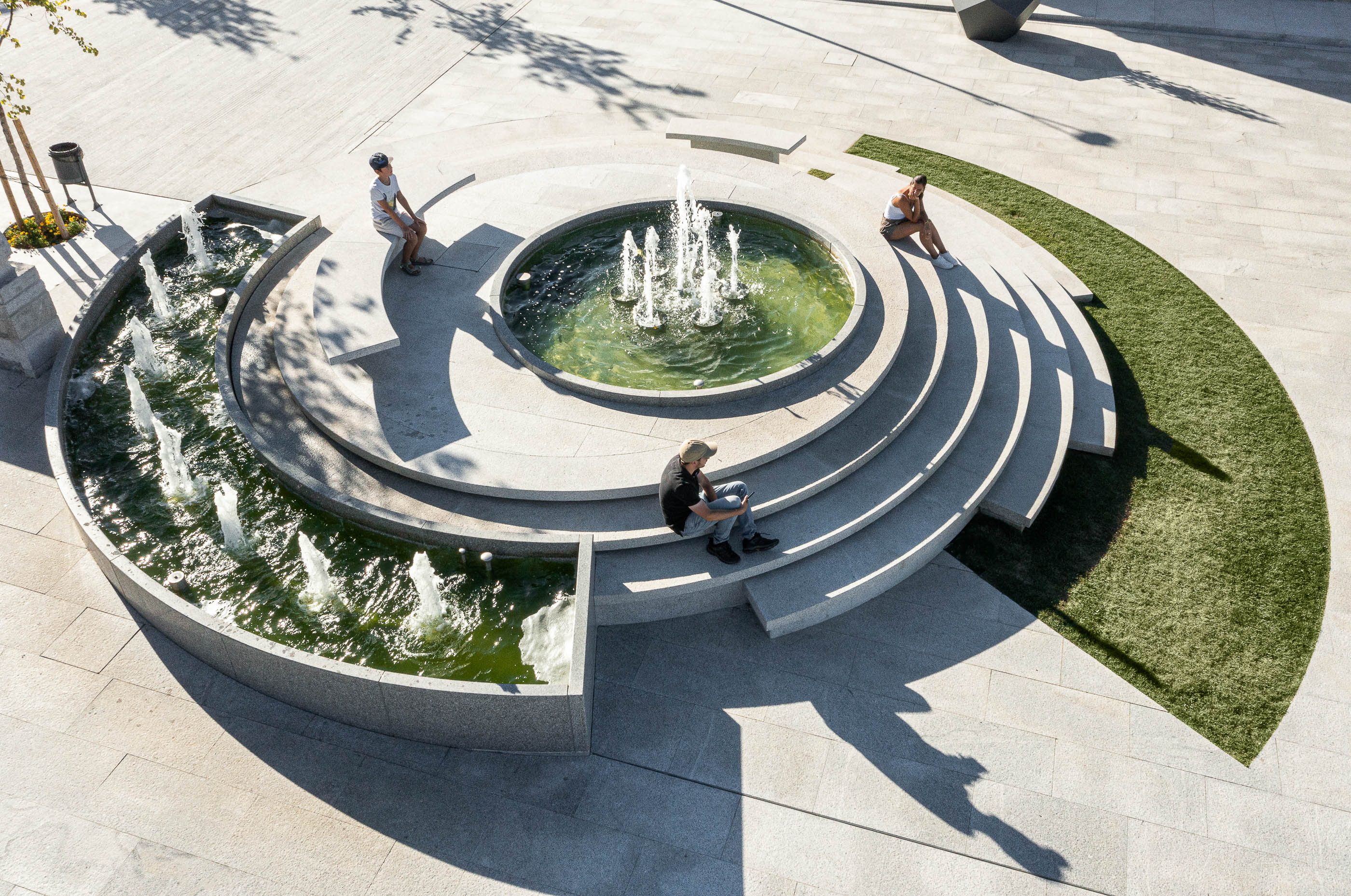 Praça: Vista aérea da fonte escalonada com relvado e pessoas a relaxar. — Requalificação da Praça do Município de Ribeira de Pena arquitetura AXR - Arquitetura e Design em Vila Real