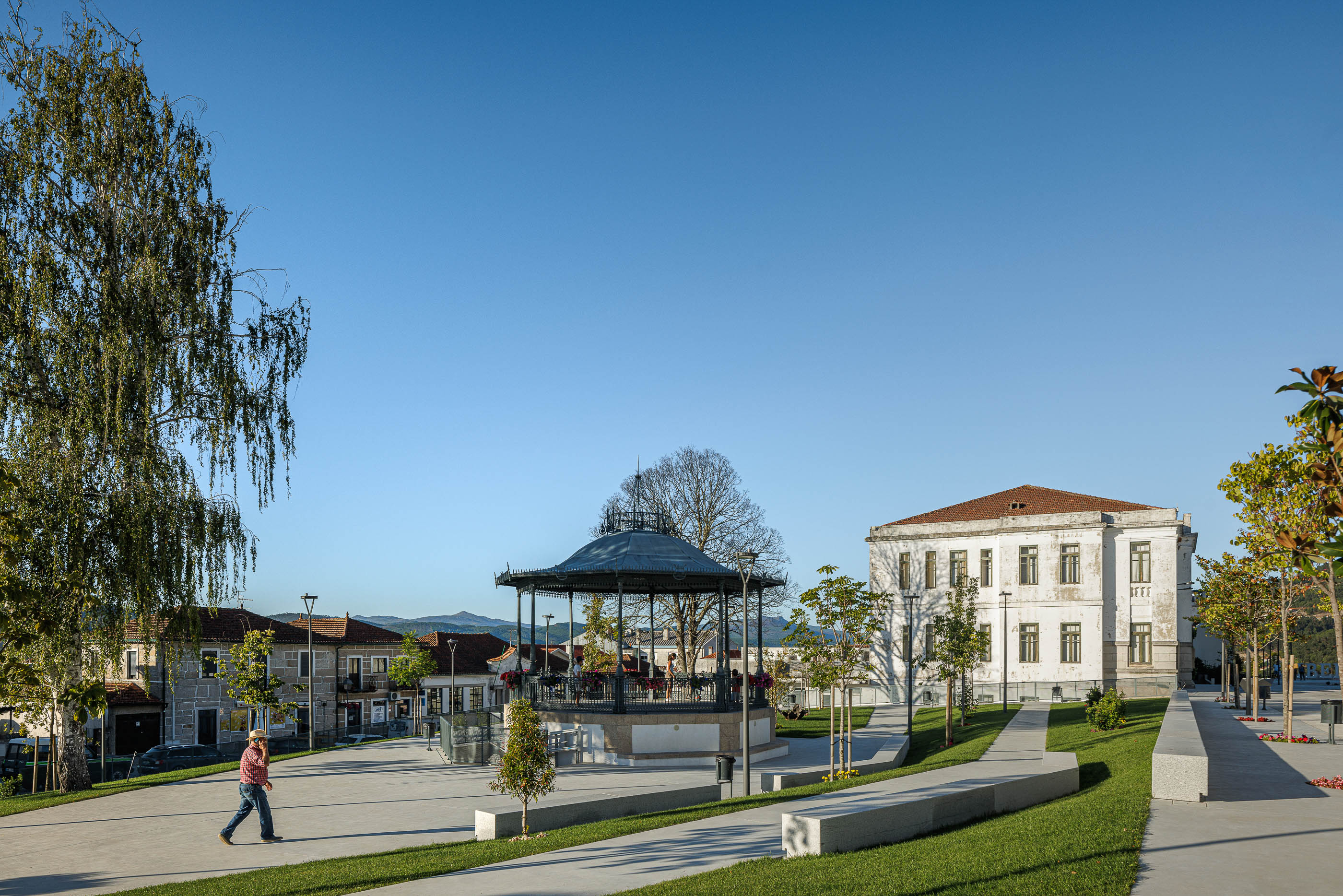 Praça: Coreto com estrutura metálica e praça com edifícios históricos ao fundo. — Requalificação da Praça do Município de Ribeira de Pena arquitetura AXR - Arquitetura e Design em Vila Real