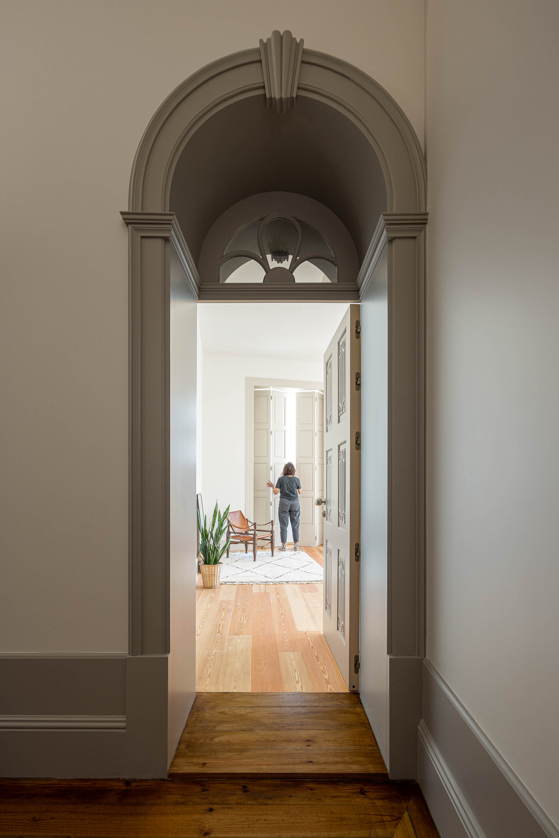 Quarto: Porta de madeira cinza em arco, pavimento em madeira clara e alcatifa geométrica. — Antigo Hotel do Louvre arquitetura Diana Barros Arquitectura em Porto
