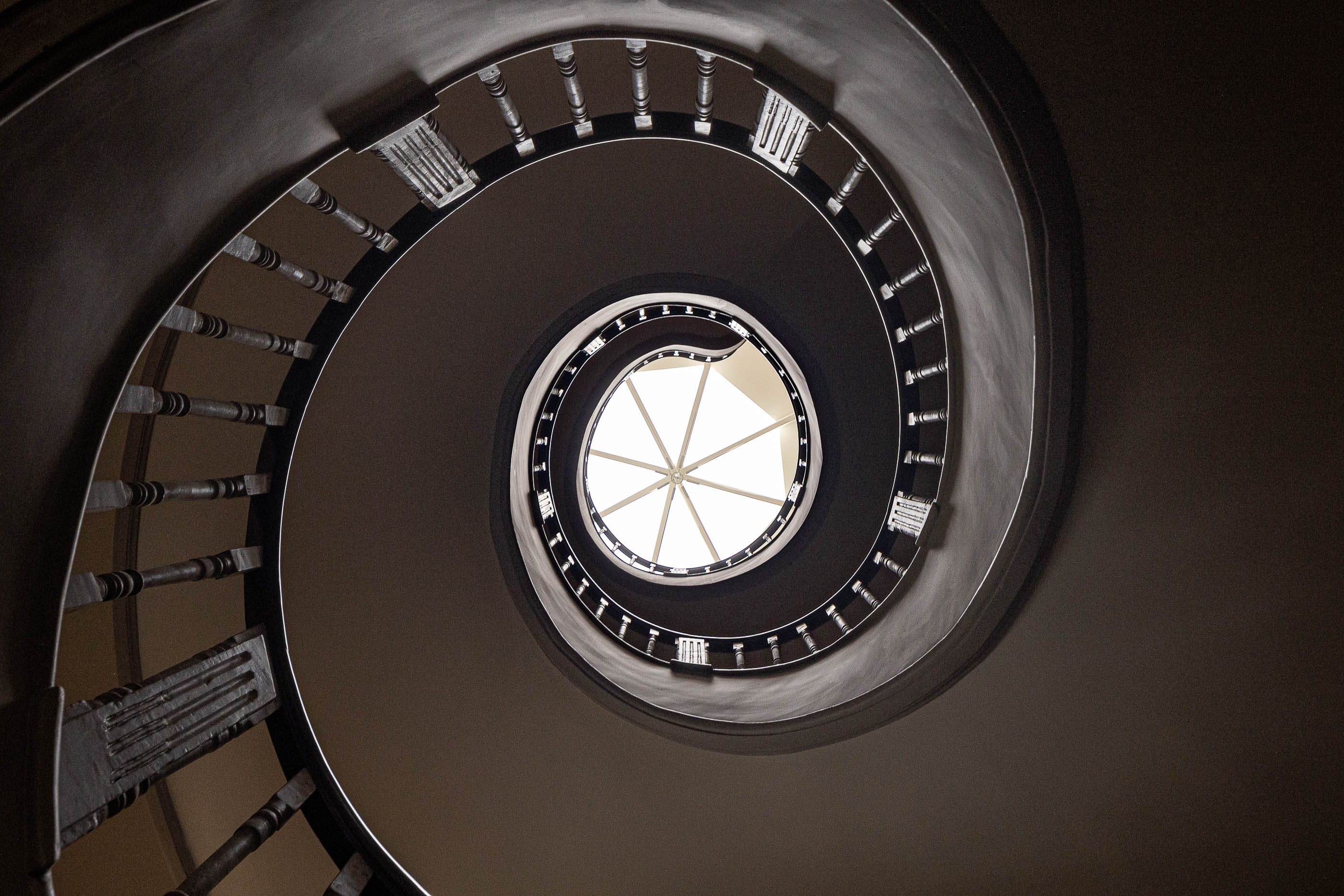Escadaria: Vista em espiral da escadaria em caracol, com claraboia ao centro. — Antigo Hotel do Louvre arquitetura Diana Barros Arquitectura em Porto