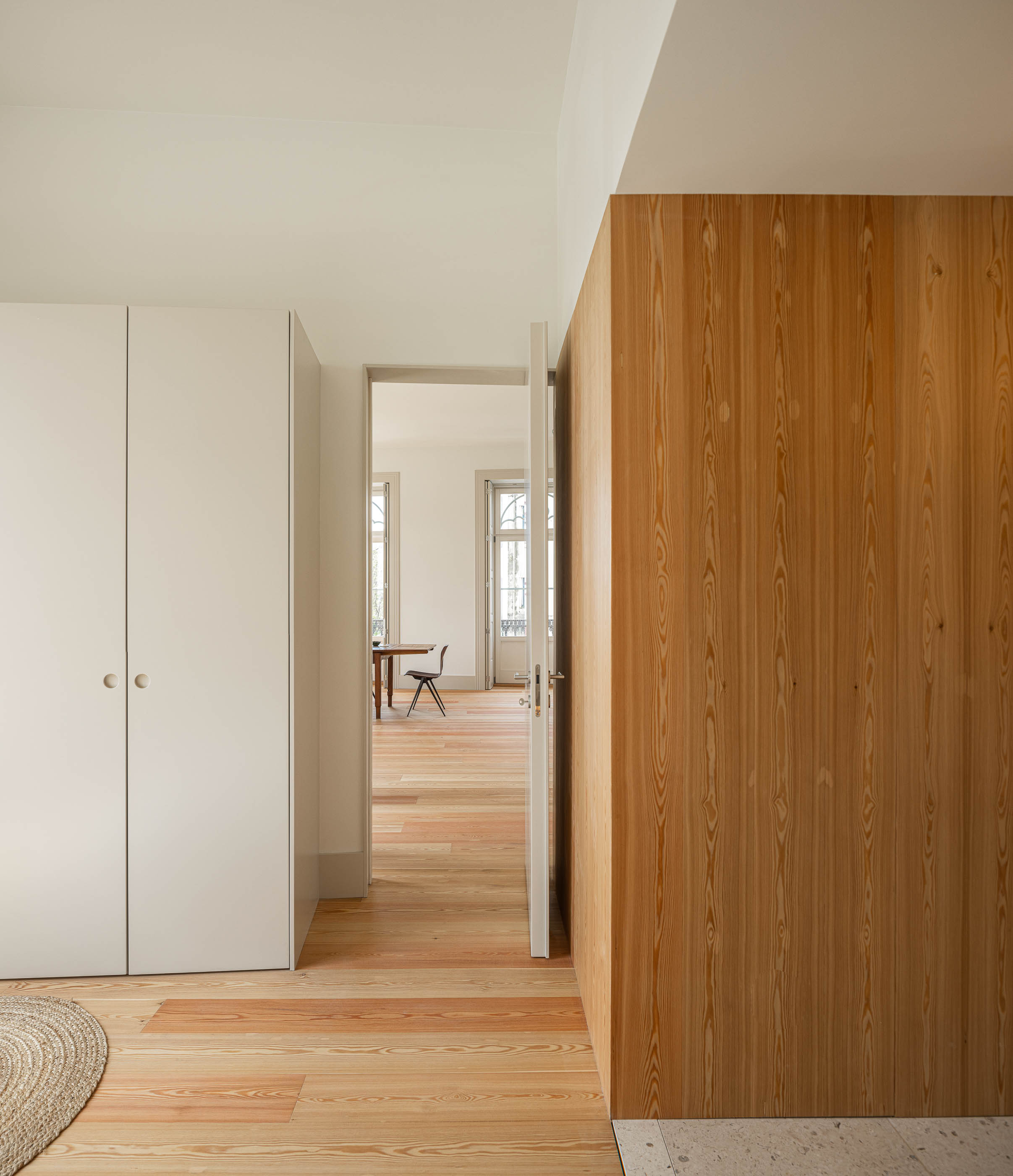 Quarto: Roupeiro branco, painel de madeira clara e porta para a sala de jantar. — Antigo Hotel do Louvre arquitetura Diana Barros Arquitectura em Porto