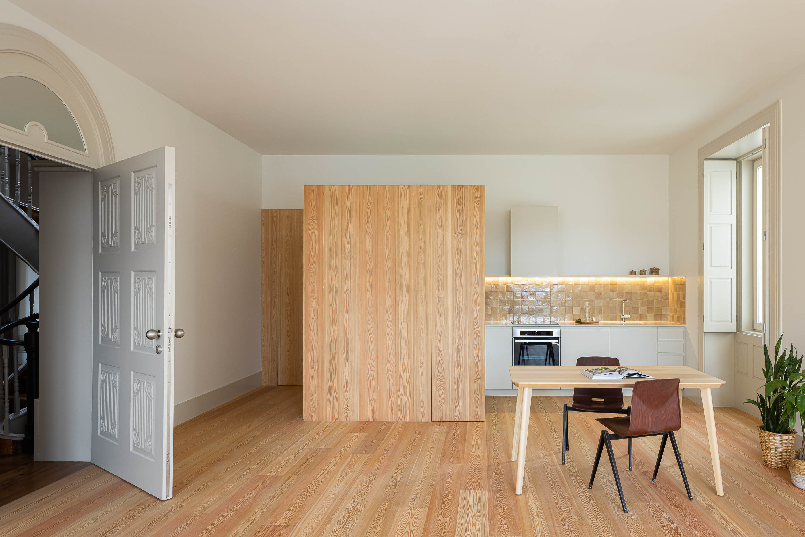 Sala de jantar/Cozinha: Espaço amplo com cozinha moderna, mesa de jantar e painéis de madeira clara. — Antigo Hotel do Louvre arquitetura Diana Barros Arquitectura em Porto