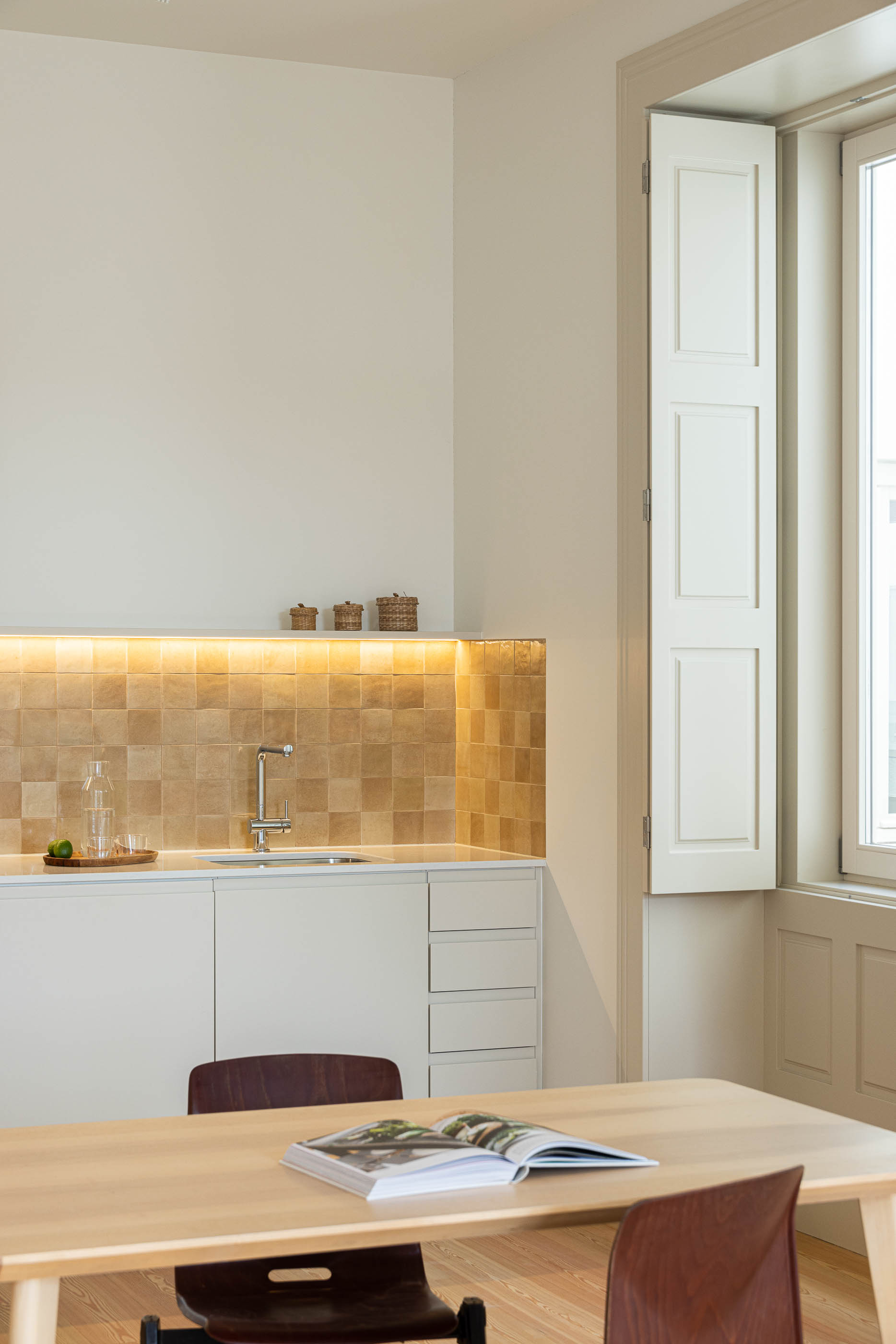Cozinha: Detalhe da cozinha com backsplash em azulejo rústico, torneira moderna e mesa de jantar. — Antigo Hotel do Louvre arquitetura Diana Barros Arquitectura em Porto