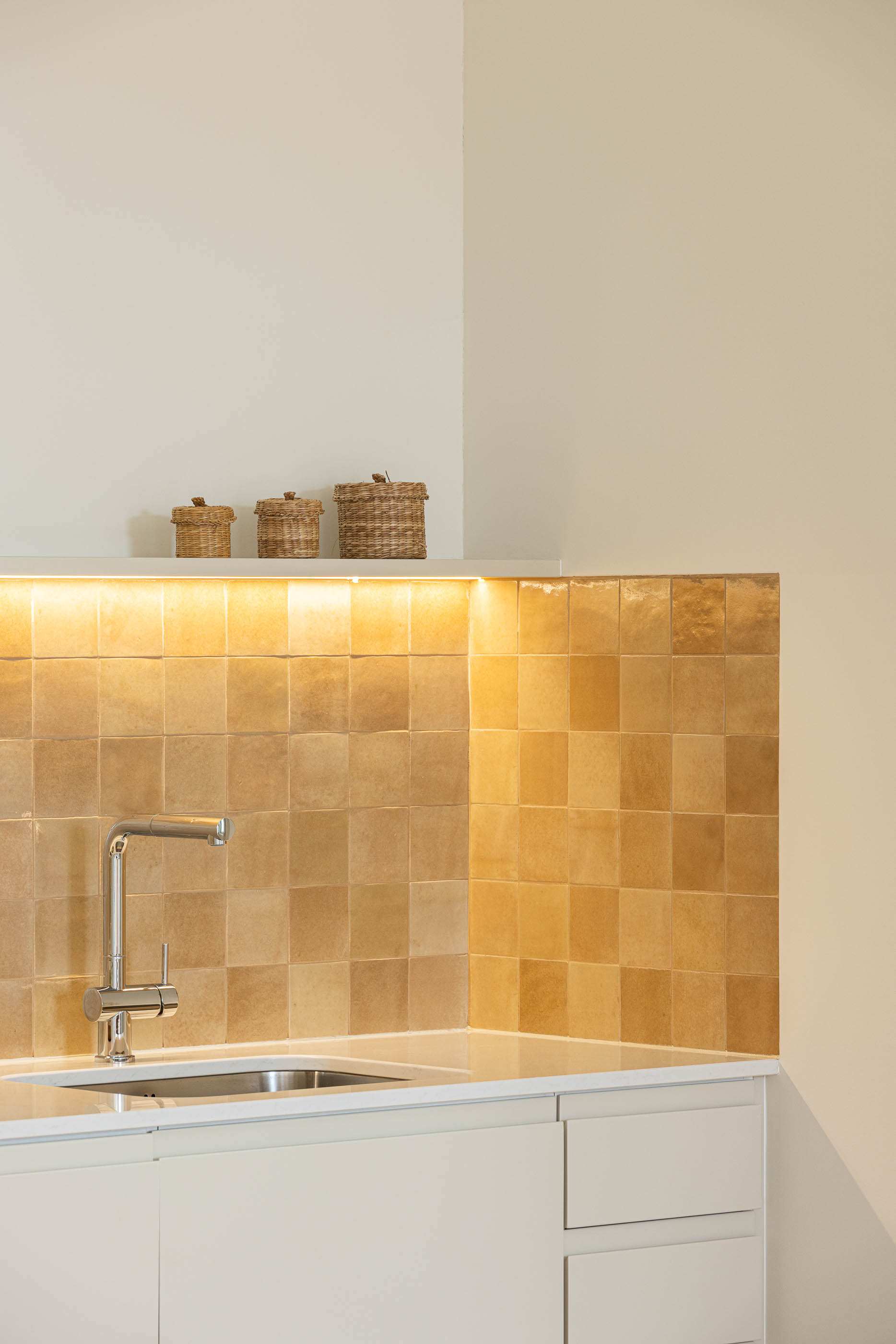 Cozinha: Detalhe da bancada da cozinha com backsplash em azulejo rústico e prateleira com cestos. — Antigo Hotel do Louvre arquitetura Diana Barros Arquitectura em Porto