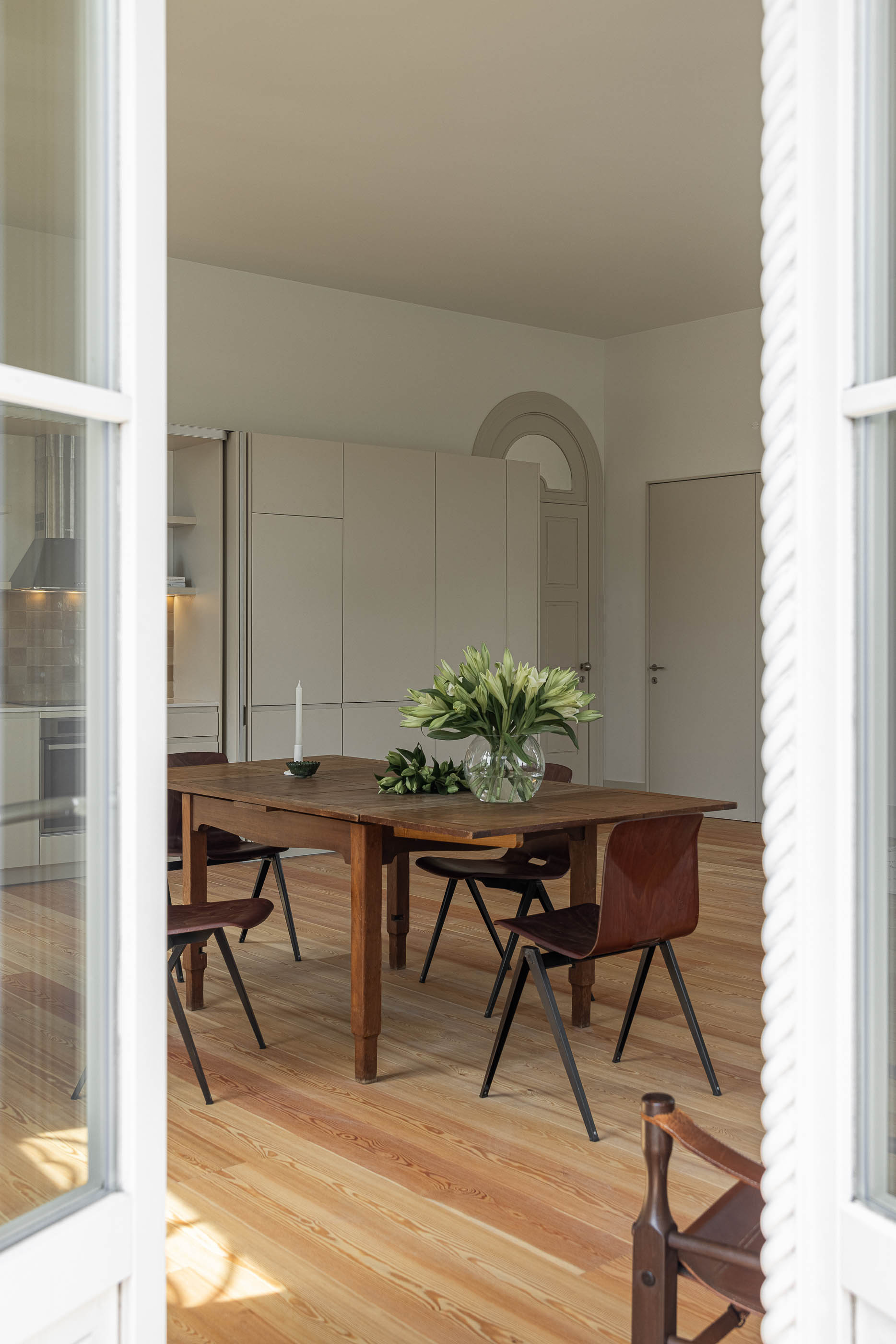Sala de jantar: Vista da cozinha através da janela da sala de jantar, com mesa de madeira rústica. — Antigo Hotel do Louvre arquitetura Diana Barros Arquitectura em Porto