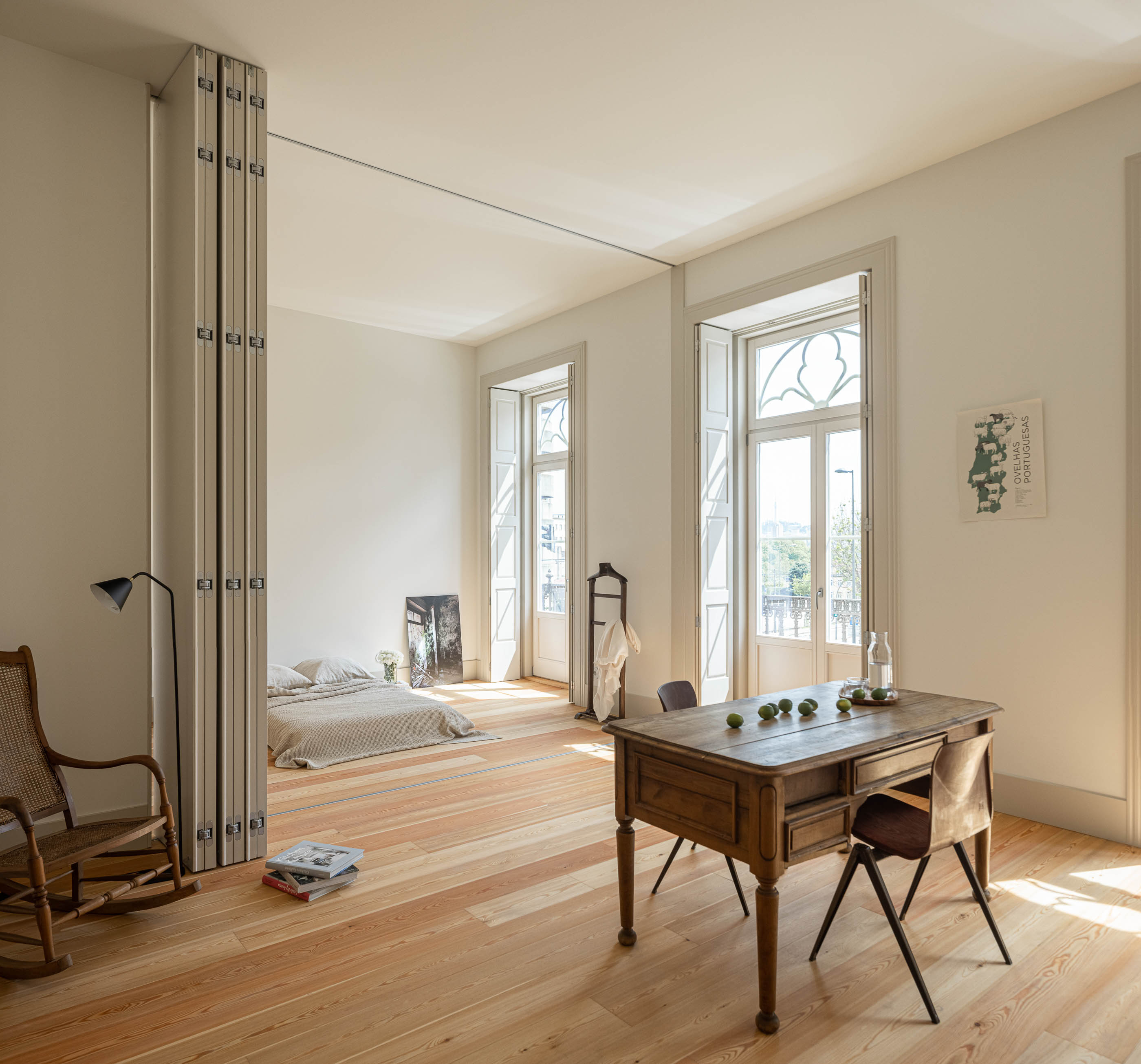 Quarto/Escritório: Quarto com divisórias de correr, secretária de madeira rústica e cadeira de design. — Antigo Hotel do Louvre arquitetura Diana Barros Arquitectura em Porto
