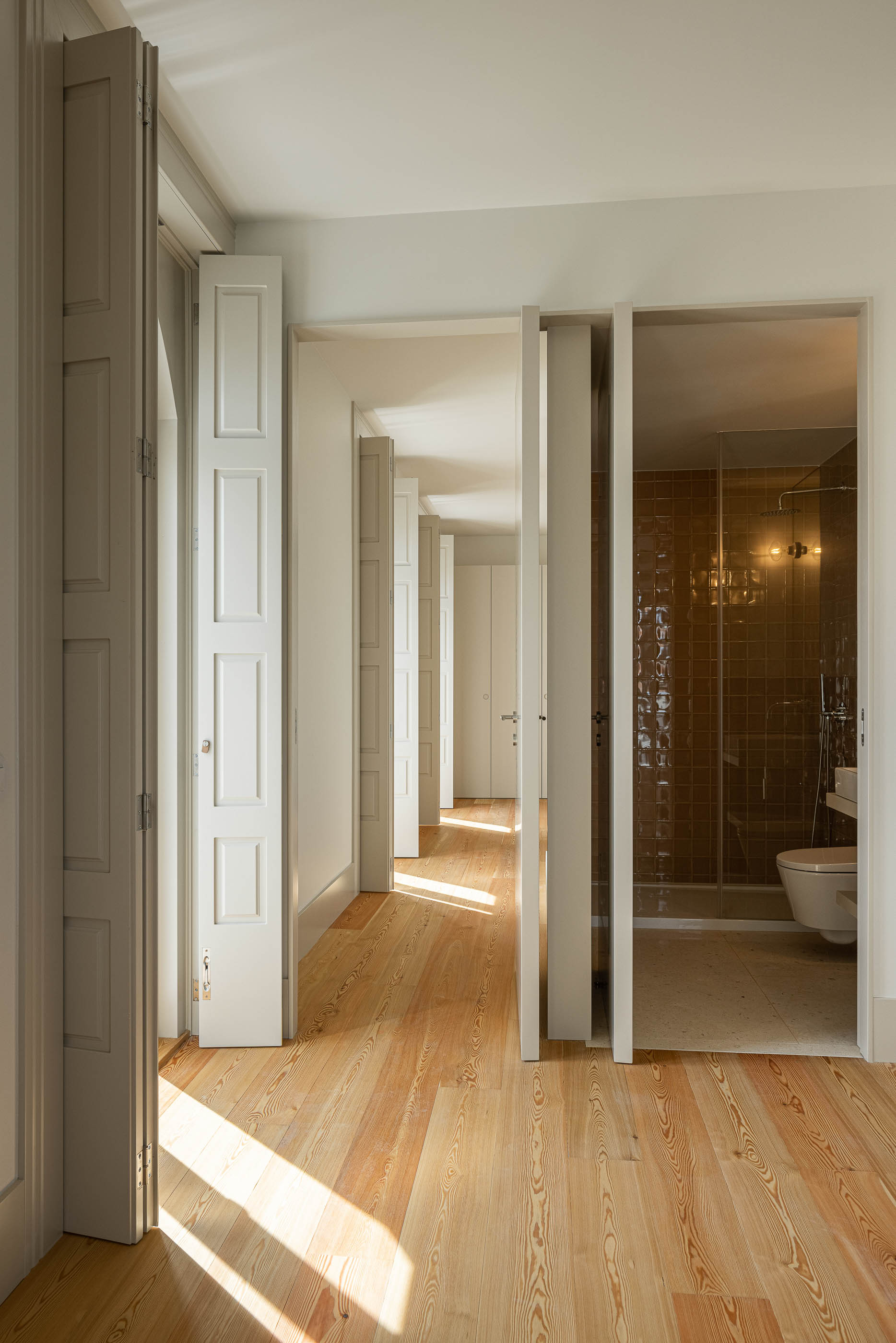 Corredor: Corredor com portas para a casa de banho e outros espaços, pavimento em madeira. — Antigo Hotel do Louvre arquitetura Diana Barros Arquitectura em Porto