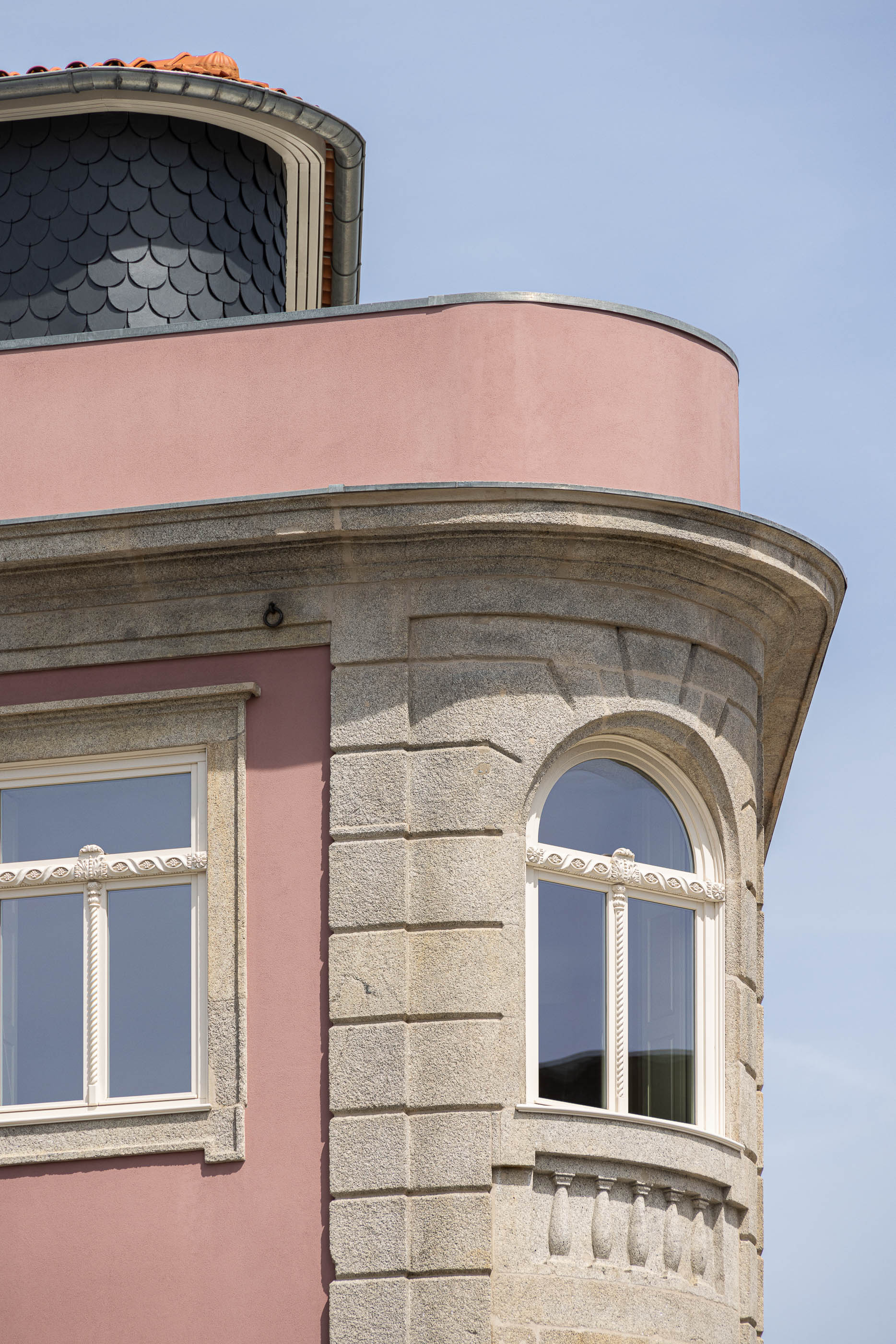 Exterior: Detalhe da fachada do edifício com cantaria em pedra e revestimento rosa. — Antigo Hotel do Louvre arquitetura Diana Barros Arquitectura em Porto