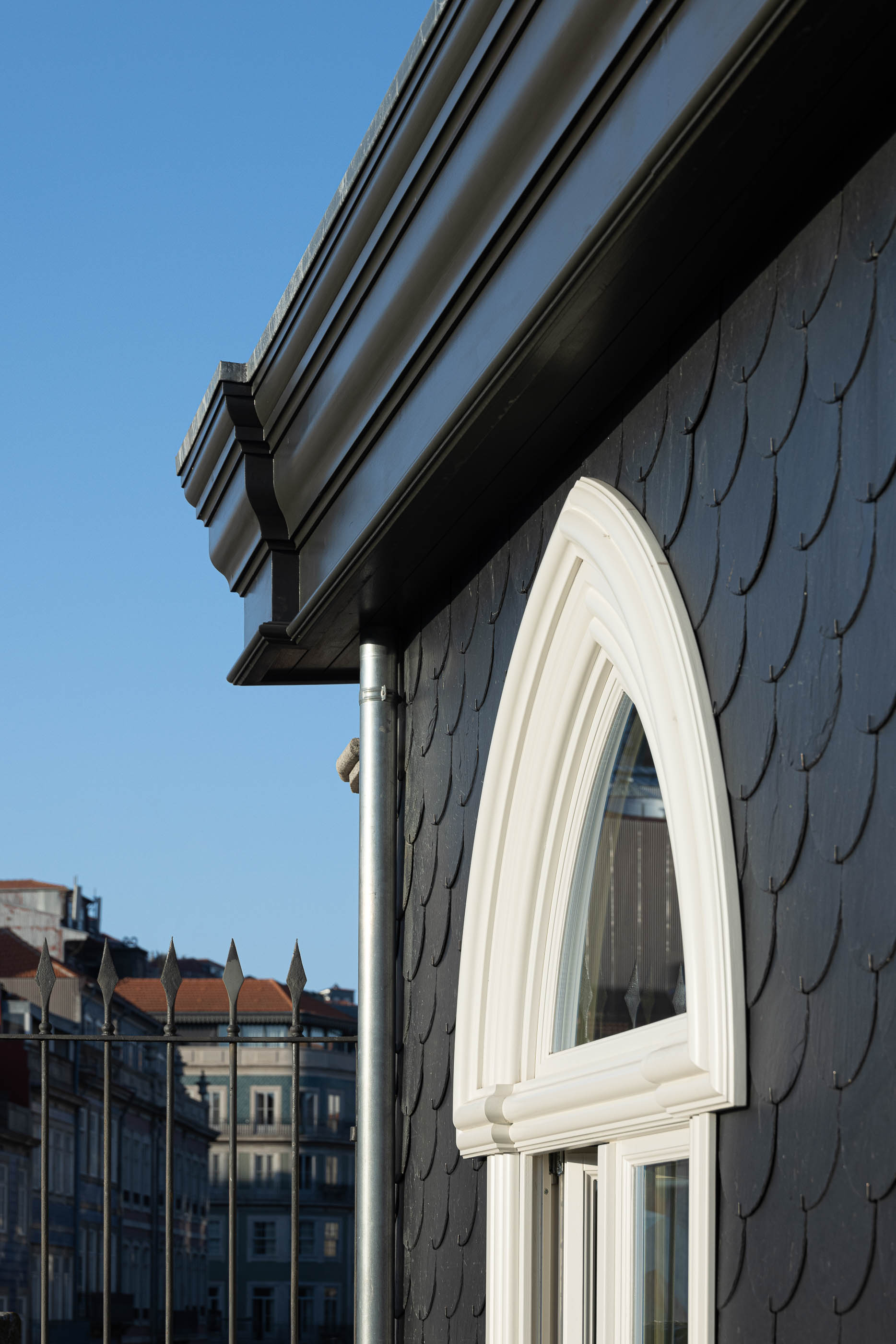 Exterior: Detalhe do telhado em escamas pretas com janela em arco branca e caleira preta. — Edifício de Mouzinho da Silveira arquitetura Diana Barros Arquitectura em Porto
