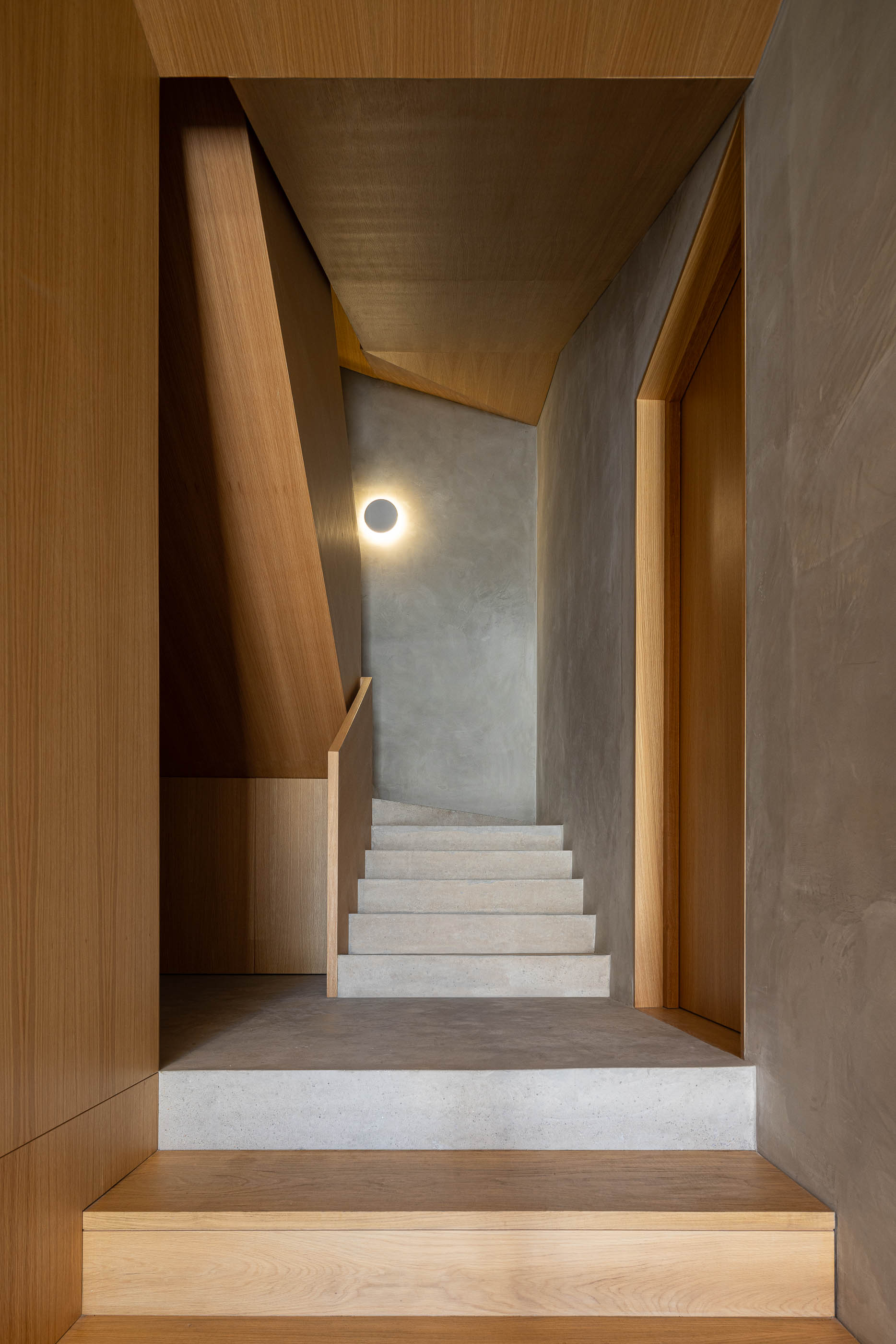 Escadas: Degraus em pedra clara com paredes em madeira e candeeiro circular. — Edifício de Mouzinho da Silveira arquitetura Diana Barros Arquitectura em Porto