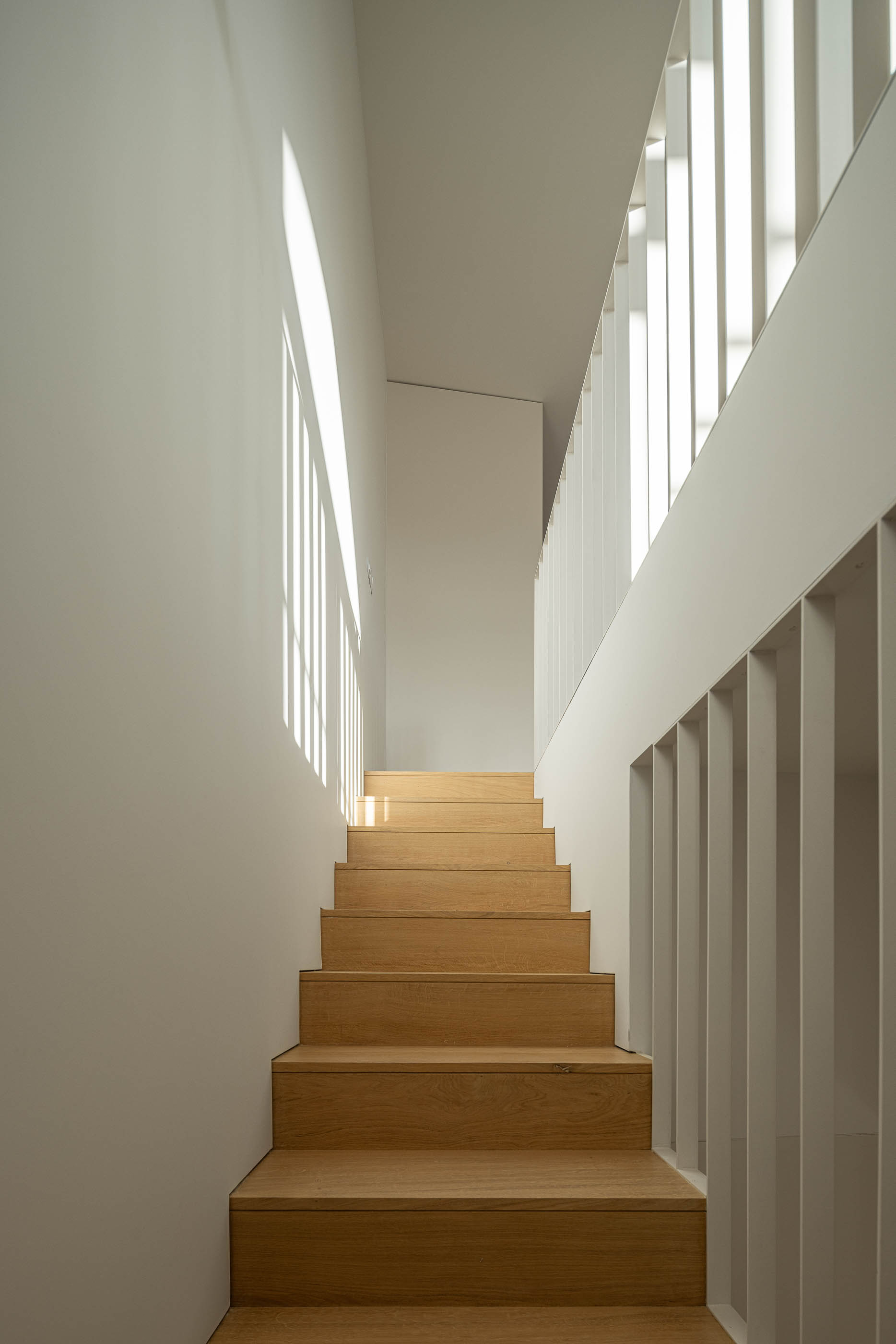 Escadas: Escada em madeira clara com corrimão branco e luz natural. — Edifício de Mouzinho da Silveira arquitetura Diana Barros Arquitectura em Porto
