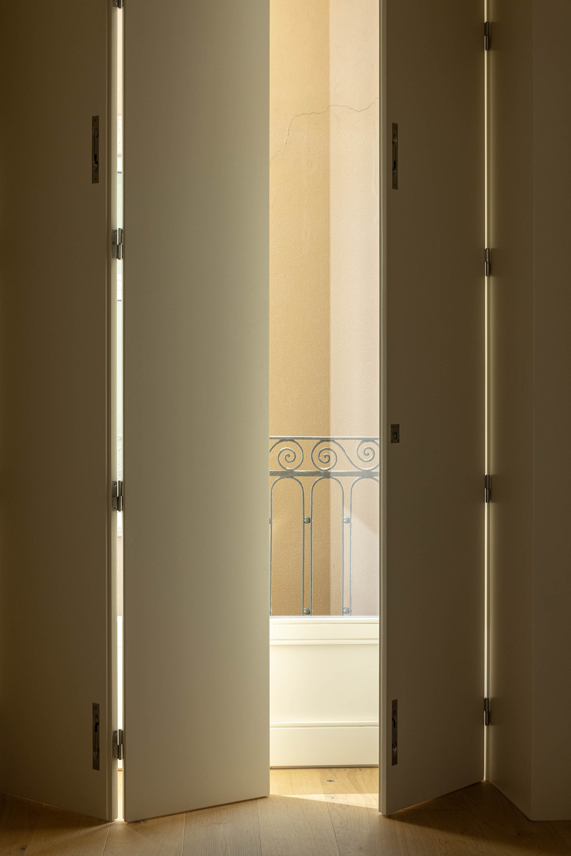 Quarto: Detalhe das portadas dobráveis brancas com vista para a varanda. — Edifício de Mouzinho da Silveira arquitetura Diana Barros Arquitectura em Porto