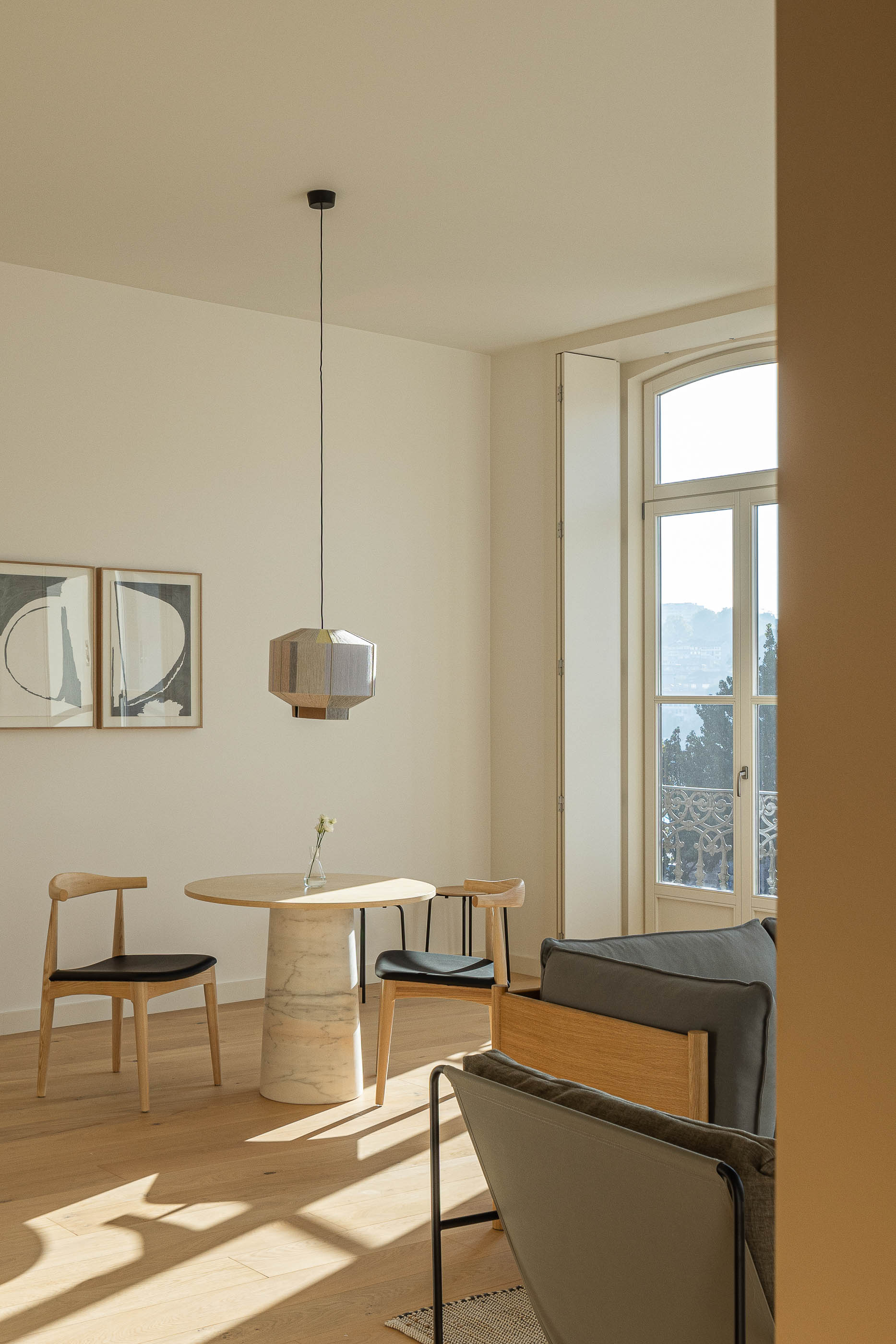 Sala de estar: Vista da sala com sofá, cadeiras, mesa redonda e quadros na parede. — Edifício de Mouzinho da Silveira arquitetura Diana Barros Arquitectura em Porto