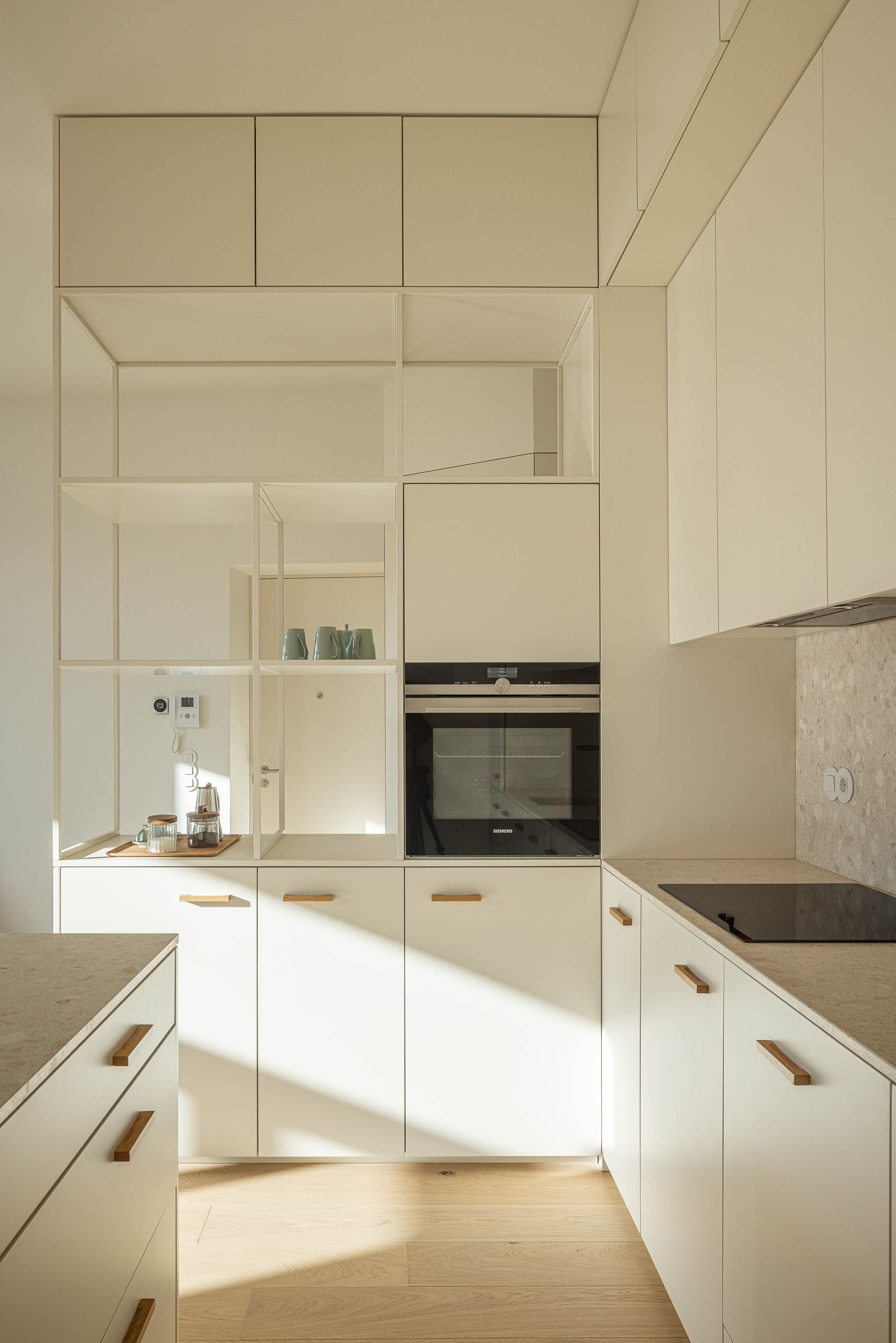 Cozinha: Armários brancos com puxadores em madeira, bancada em pedra e prateleiras abertas. — Edifício de Mouzinho da Silveira arquitetura Diana Barros Arquitectura em Porto