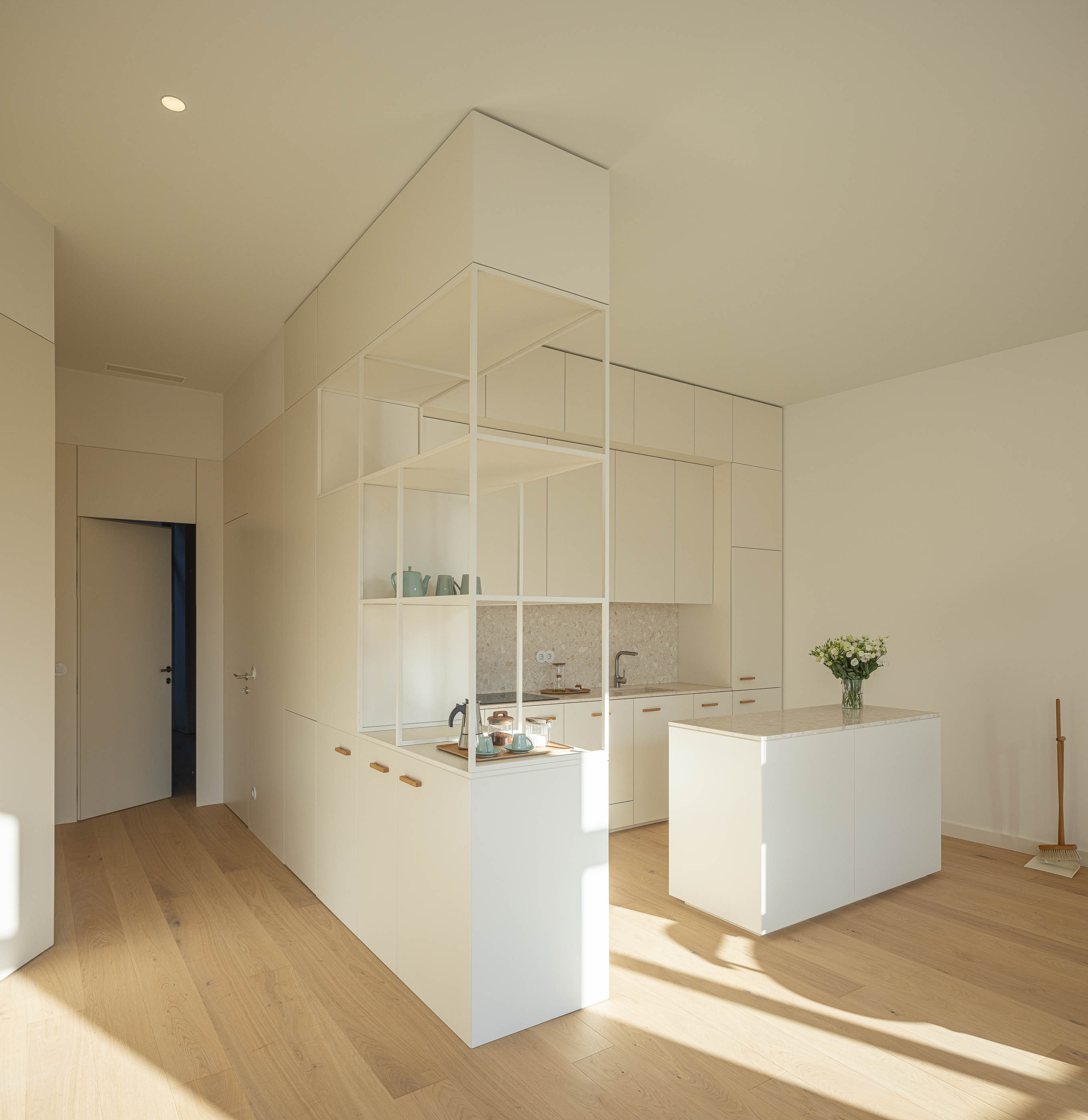 Cozinha: Vista geral da cozinha com armários brancos, ilha central e pavimento em madeira clara. — Edifício de Mouzinho da Silveira arquitetura Diana Barros Arquitectura em Porto