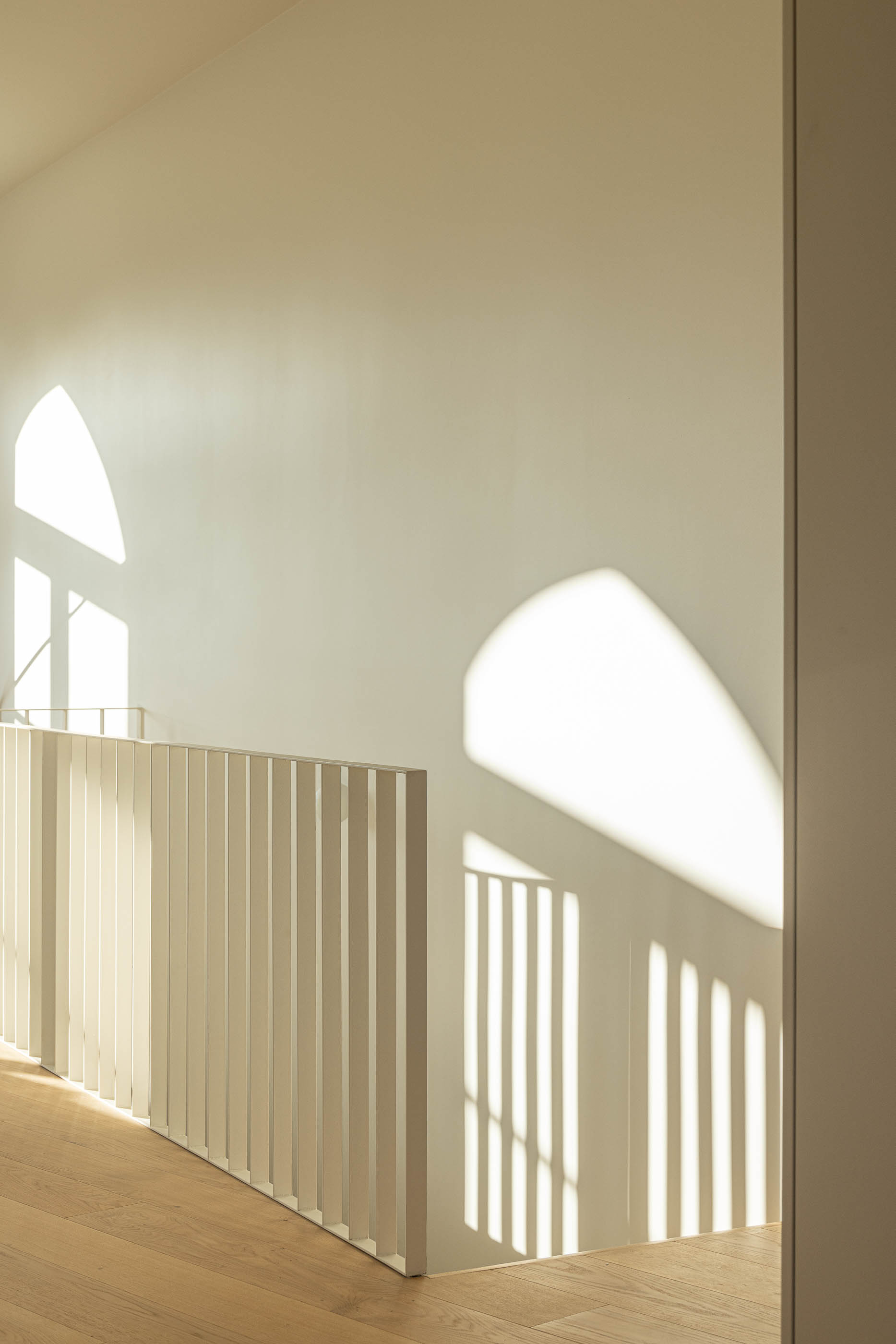 Escadas: Corrimão branco e luz natural através da janela em arco no patamar da escada. — Edifício de Mouzinho da Silveira arquitetura Diana Barros Arquitectura em Porto