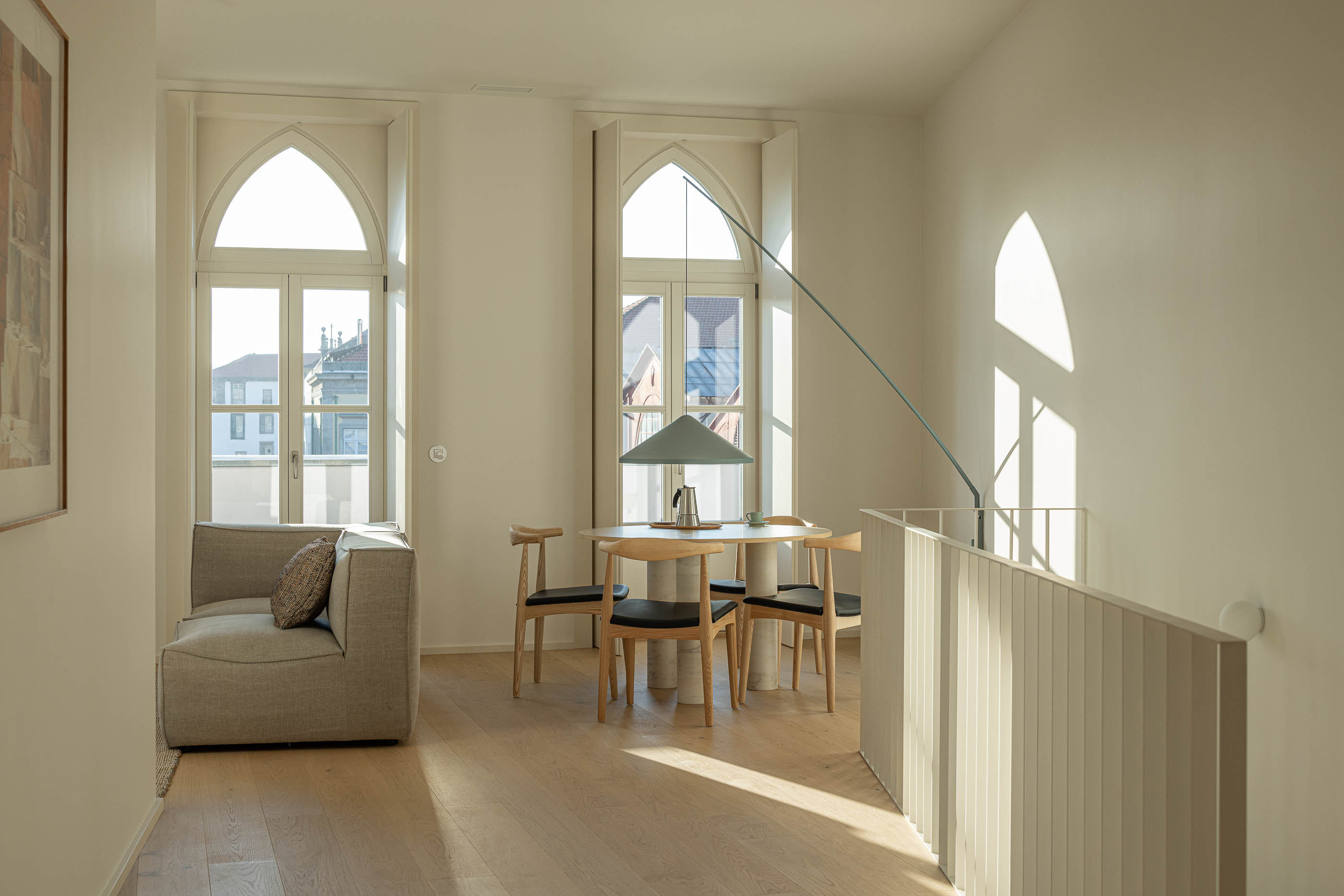 Sala de estar: Sala de estar com sofá, mesa de jantar, cadeiras e janelas em arco. — Edifício de Mouzinho da Silveira arquitetura Diana Barros Arquitectura em Porto