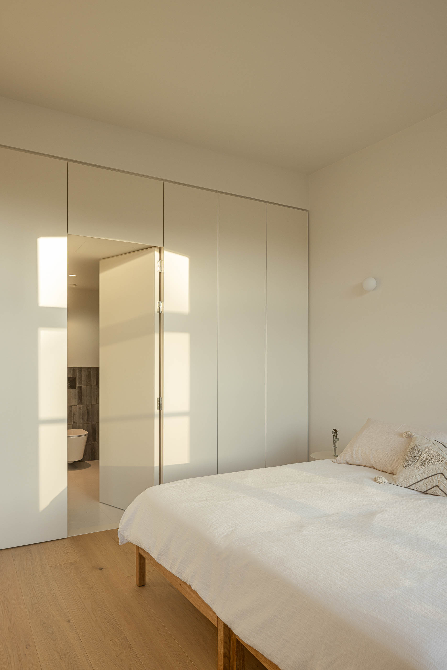 Quarto: Quarto com cama de madeira, roupeiros embutidos e porta para a casa de banho. — Edifício de Mouzinho da Silveira arquitetura Diana Barros Arquitectura em Porto