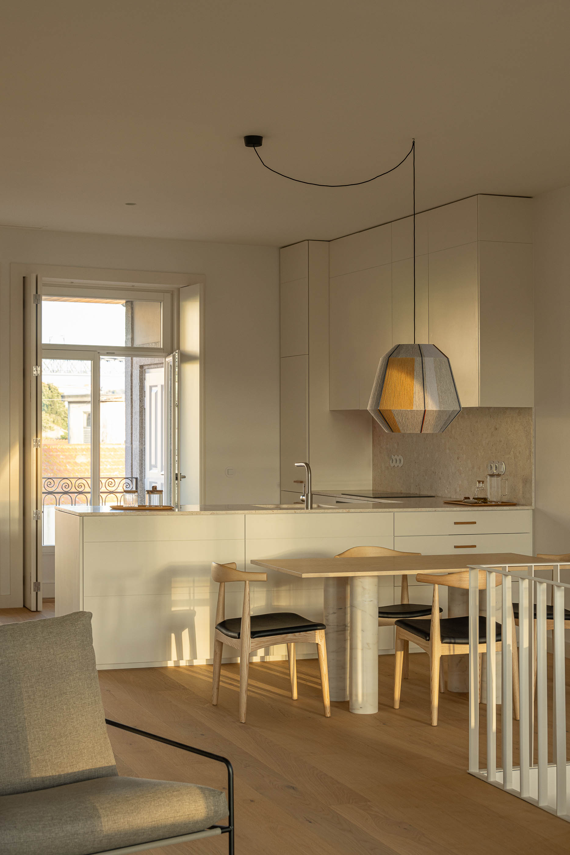 Sala de estar: Sala de estar com mesa de jantar, cadeiras, candeeiro suspenso e cozinha ao fundo. — Edifício de Mouzinho da Silveira arquitetura Diana Barros Arquitectura em Porto