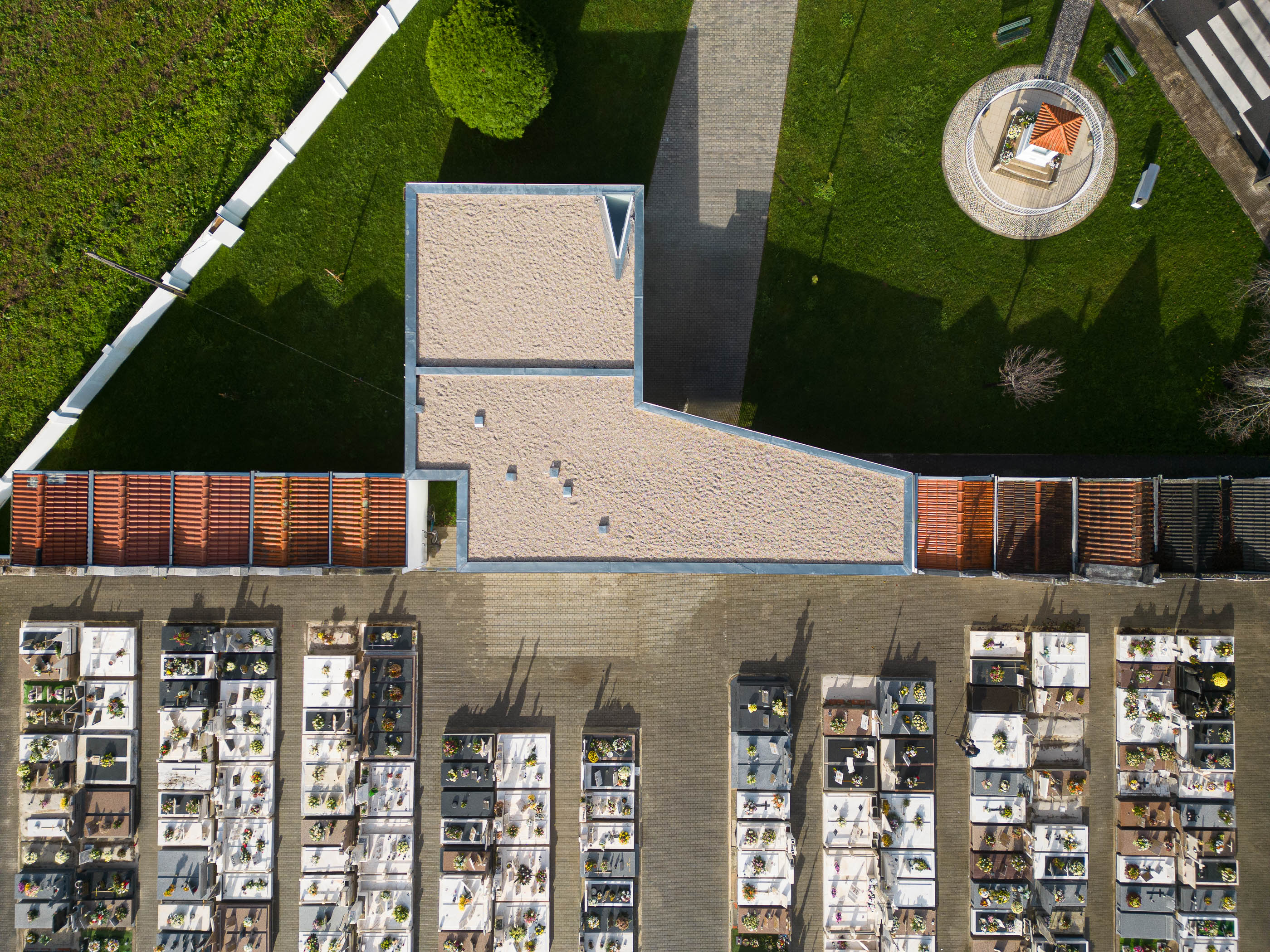 Planta: Vista aérea do telhado da casa mortuária em L, com gravilha, adjacente ao cemitério e relvado. — Casa Mortuária de Oliveirinha arquitetura Sónia Cruz Arquitectura em Aveiro