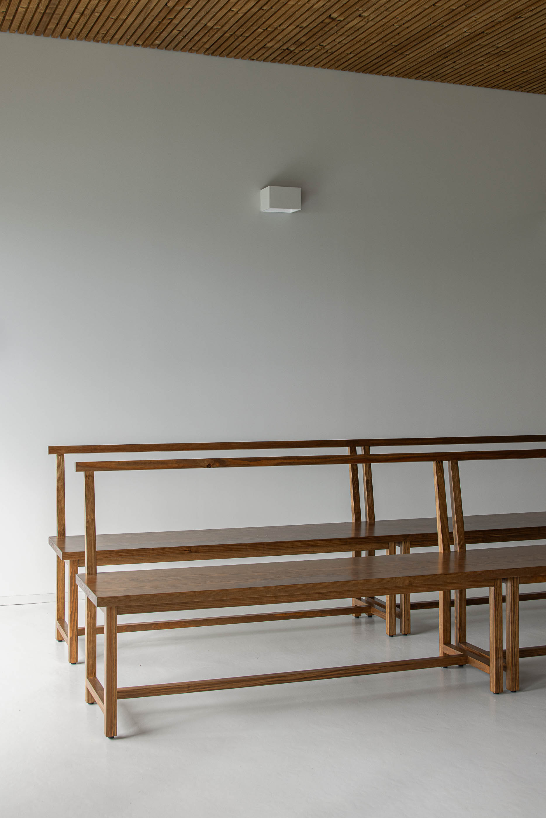 Interior: Detalhe dos bancos de madeira na sala de cerimónias com teto em madeira. — Casa Mortuária de Oliveirinha arquitetura Sónia Cruz Arquitectura em Aveiro