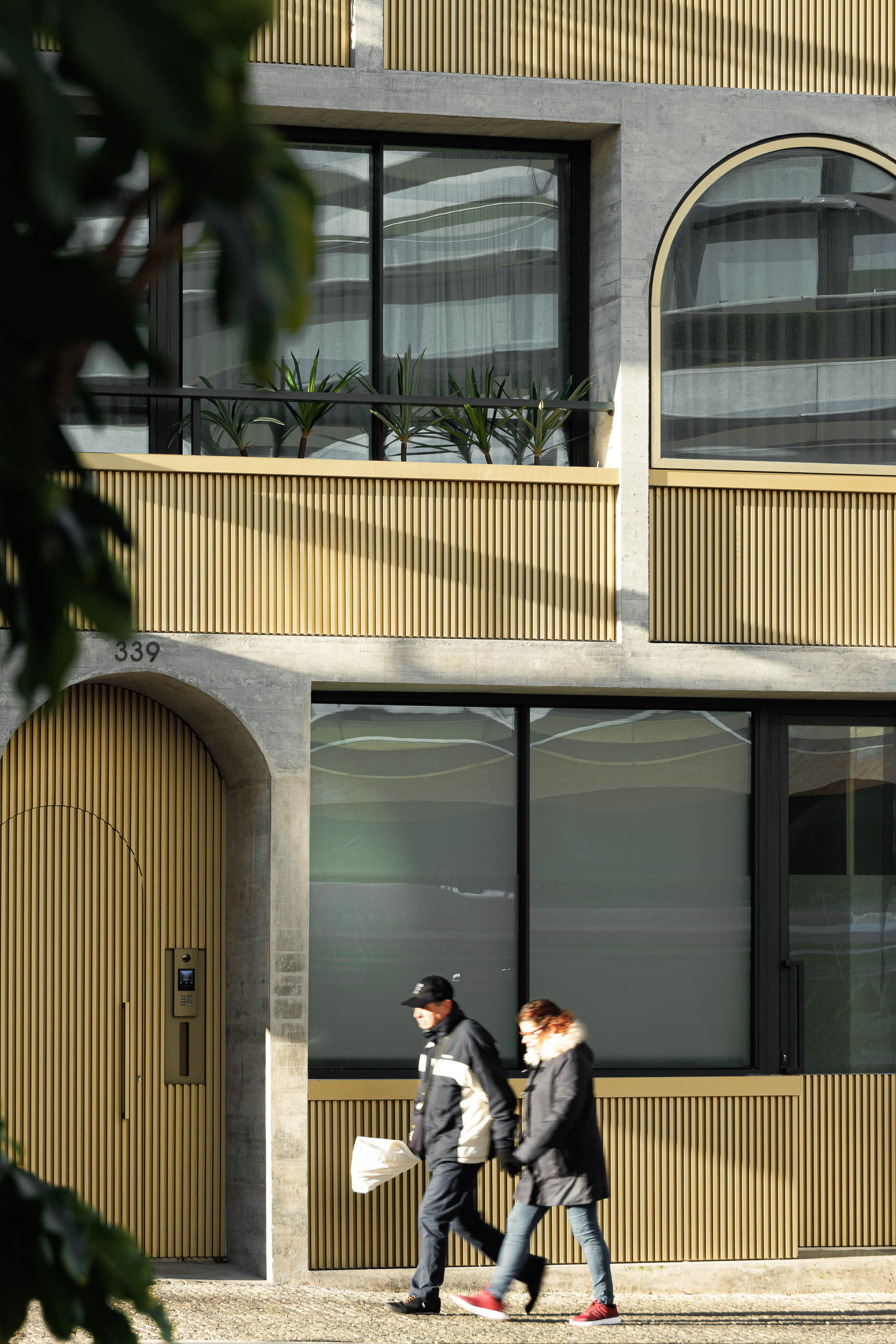 Fachada do edifício "Boavista 339" com pessoas a passar, detalhe da porta de entrada e janelas em arco. — Boavista 339 arquitetura Paulo Merlini Architects em Porto