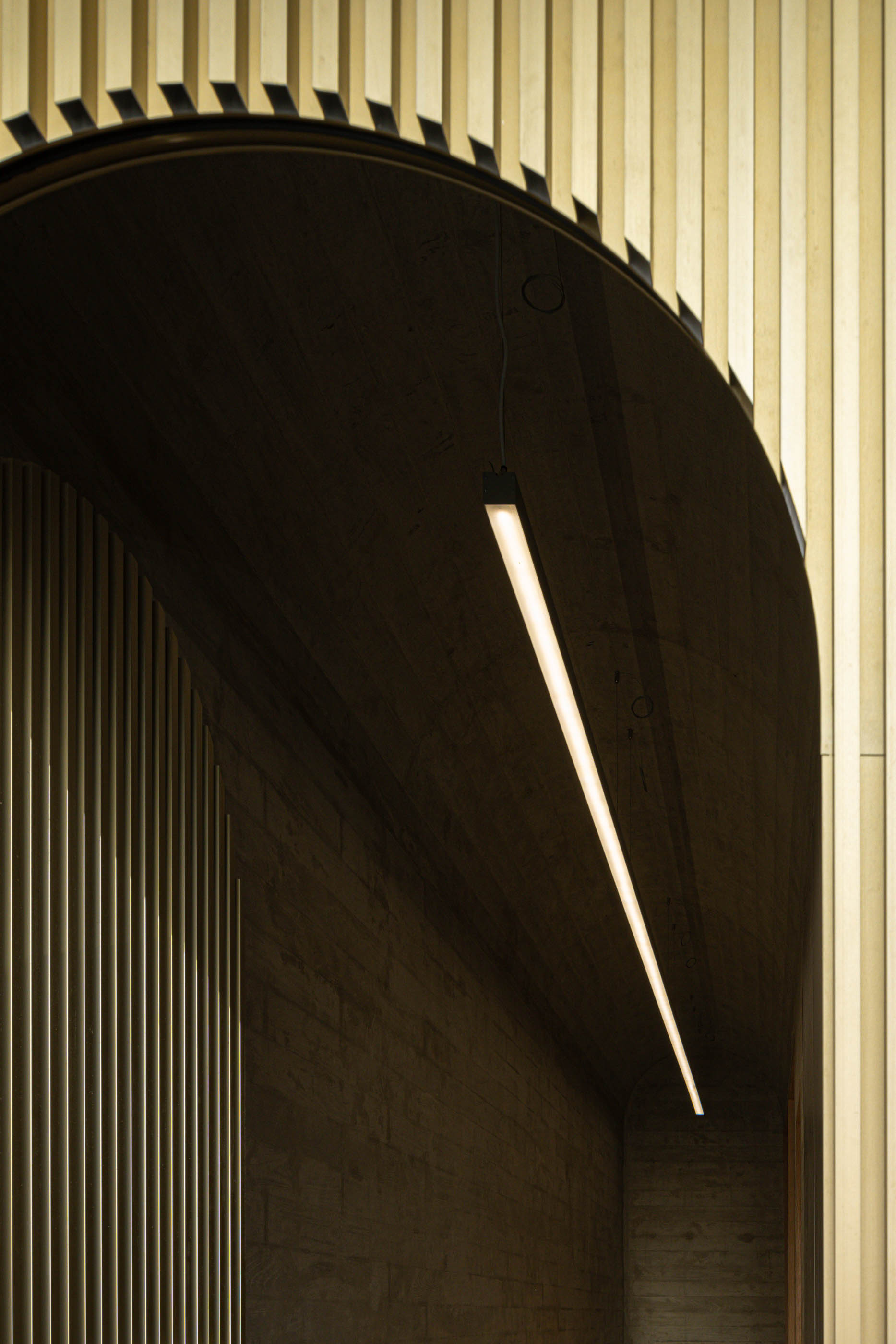 Detalhe da iluminação linear no teto da entrada do edifício, com revestimento em ripas verticais. — Boavista 339 arquitetura Paulo Merlini Architects em Porto