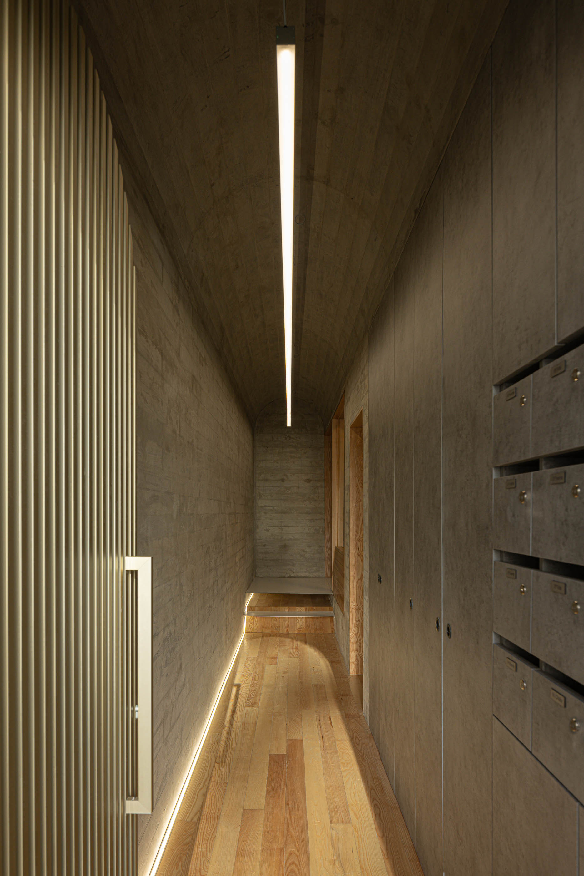 Corredor interior com iluminação linear, pavimento em madeira e caixas de correio embutidas na parede. — Boavista 339 arquitetura Paulo Merlini Architects em Porto