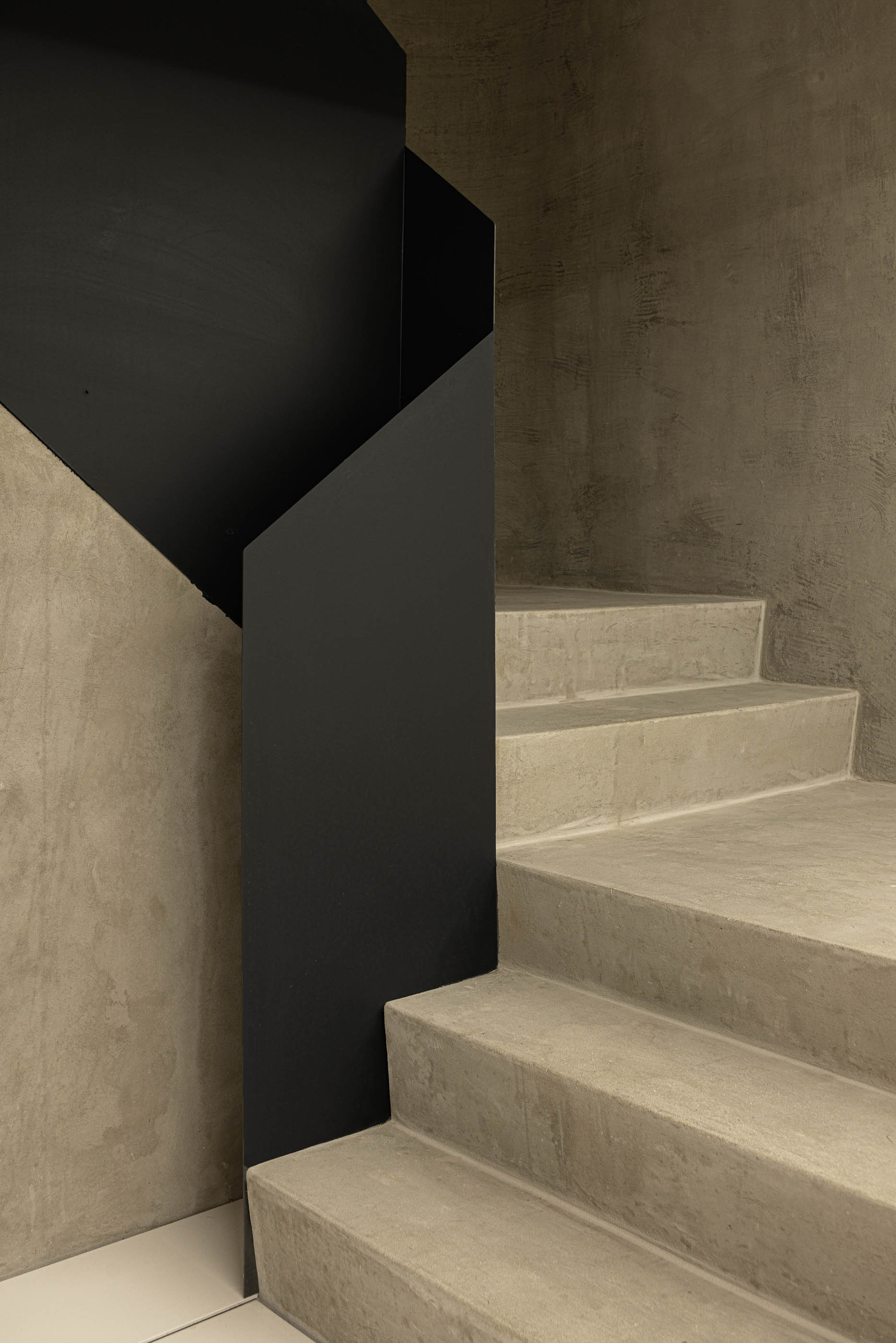 Detalhe da escadaria em betão com guarda em metal preto, mostrando a textura do material. — Boavista 339 arquitetura Paulo Merlini Architects em Porto