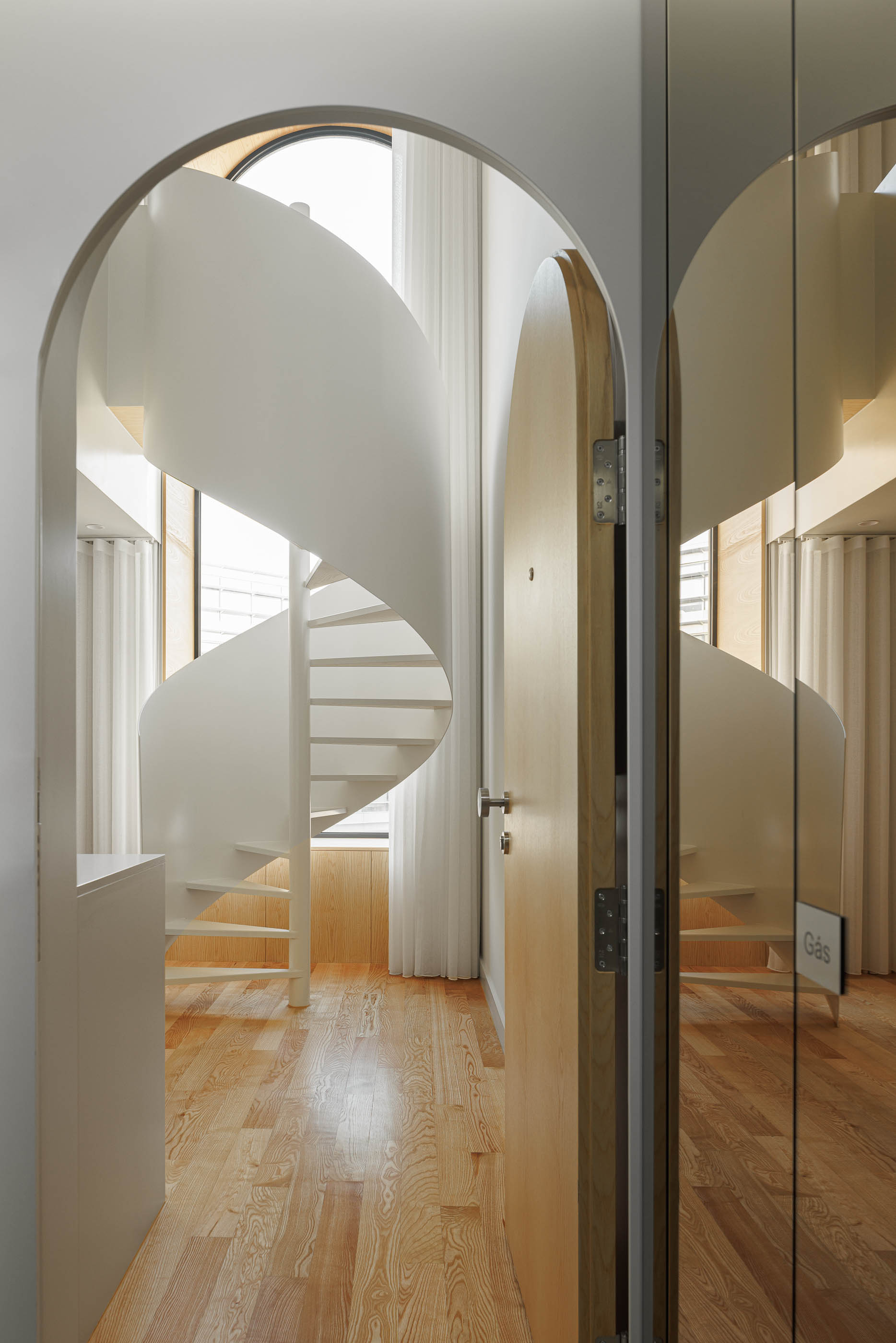 Hall de entrada com porta em arco e escada em caracol branca visível ao fundo. — Boavista 339 arquitetura Paulo Merlini Architects em Porto