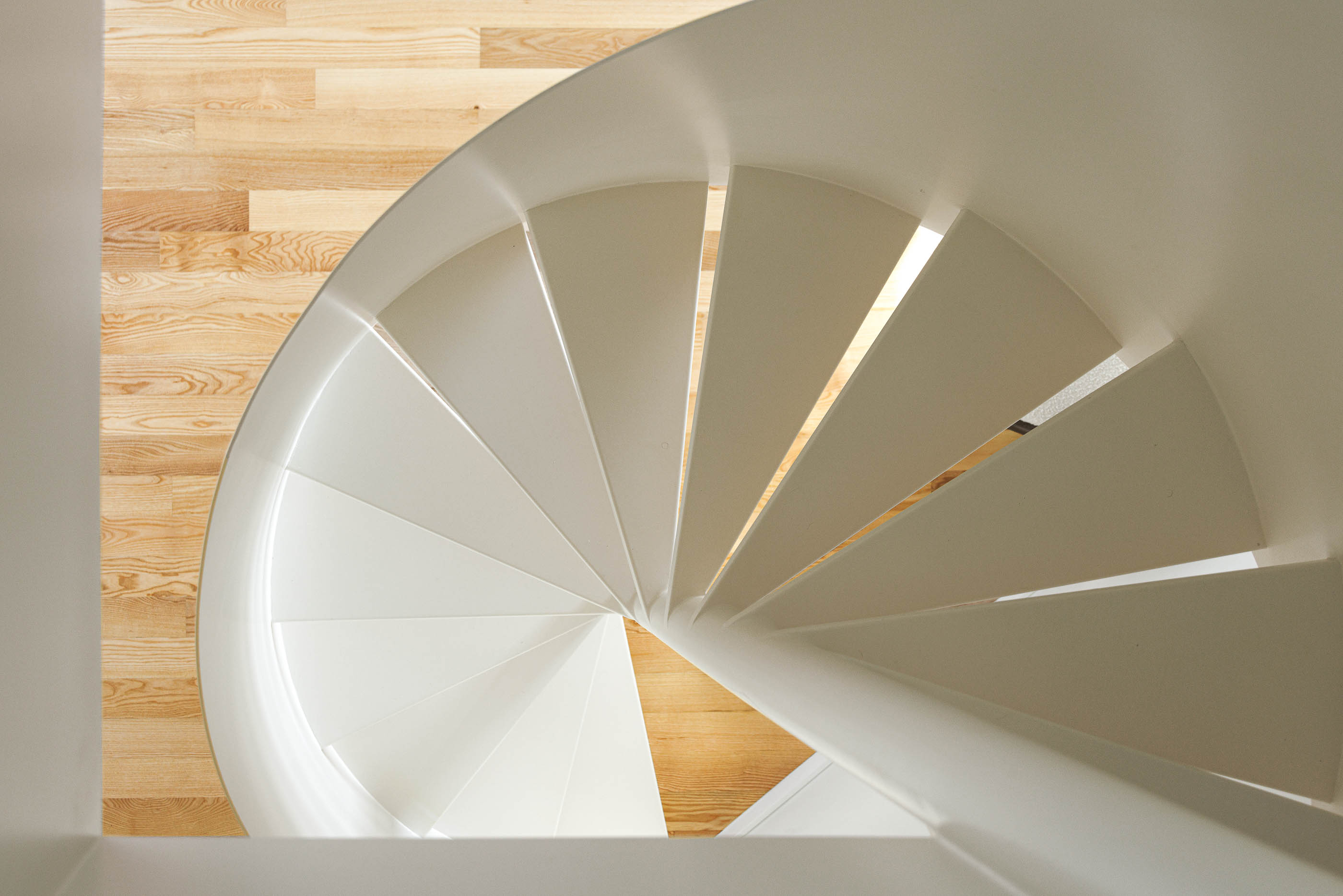 Vista de cima da escada em caracol branca, com degraus em madeira clara e pavimento em madeira. — Boavista 339 arquitetura Paulo Merlini Architects em Porto