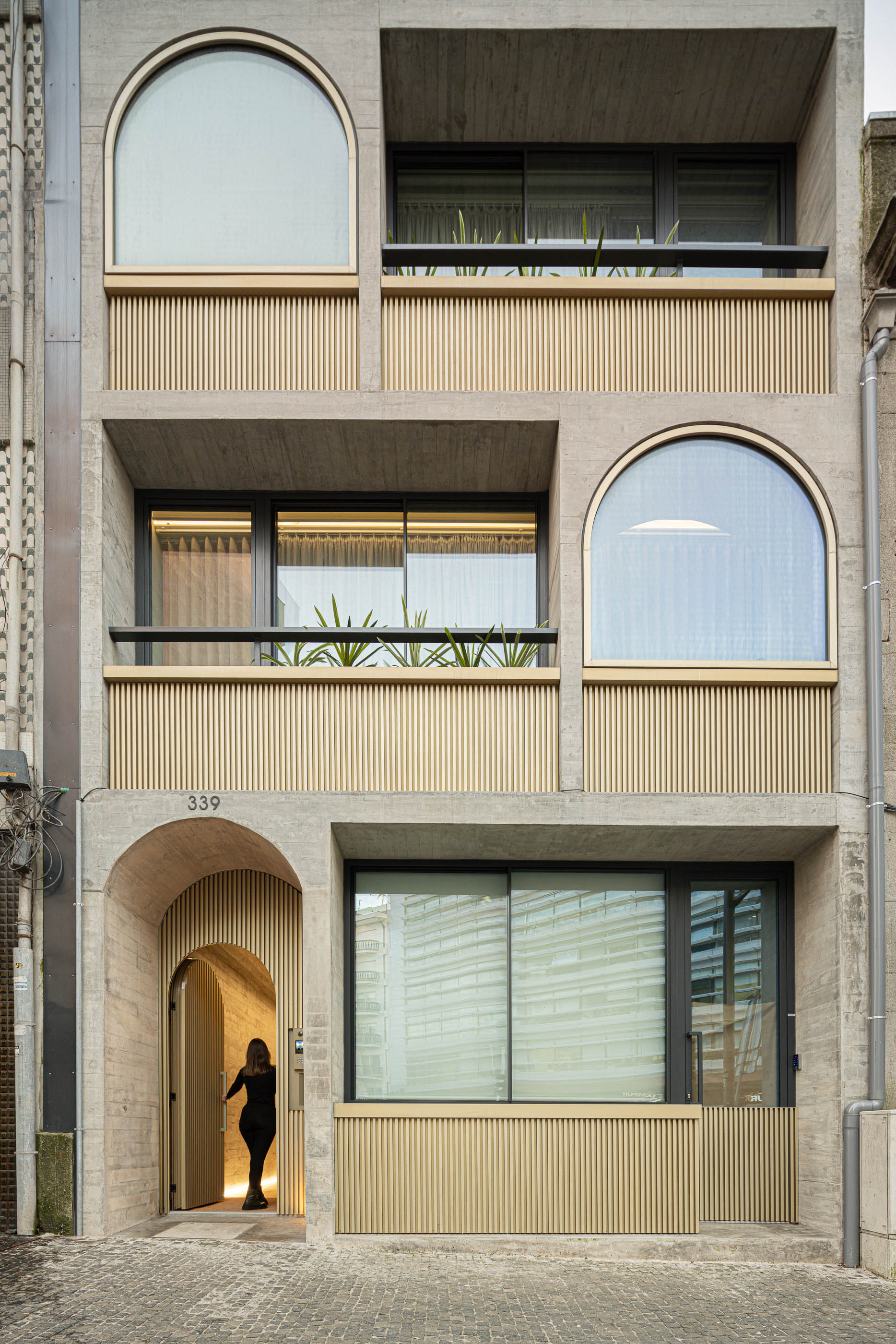 Fachada do edifício "Boavista 339" com janelas em arco e revestimento em ripas verticais. — Boavista 339 arquitetura Paulo Merlini Architects em Porto