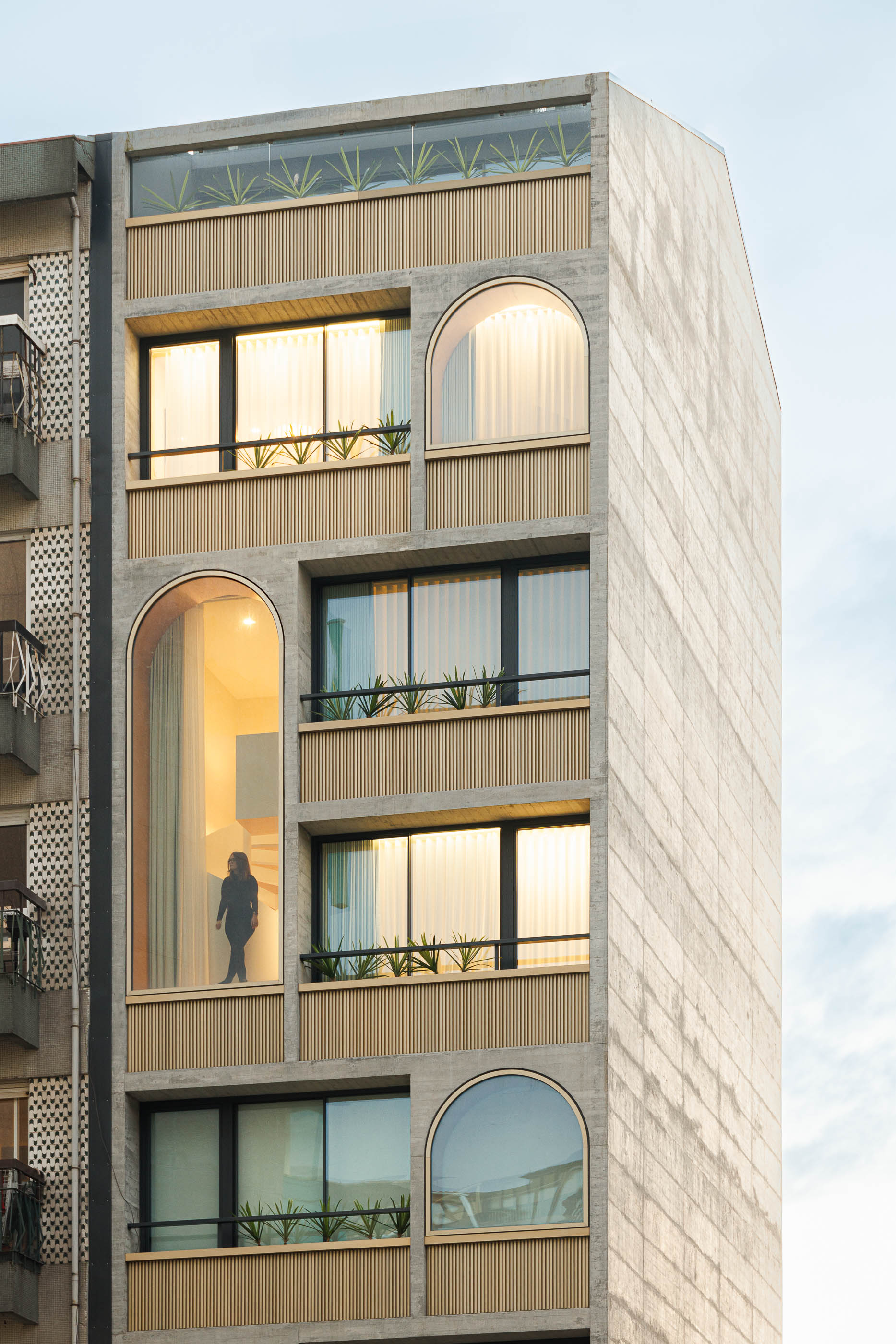 Detalhe da fachada do edifício "Boavista 339" com escada em caracol visível através de uma janela em arco. — Boavista 339 arquitetura Paulo Merlini Architects em Porto