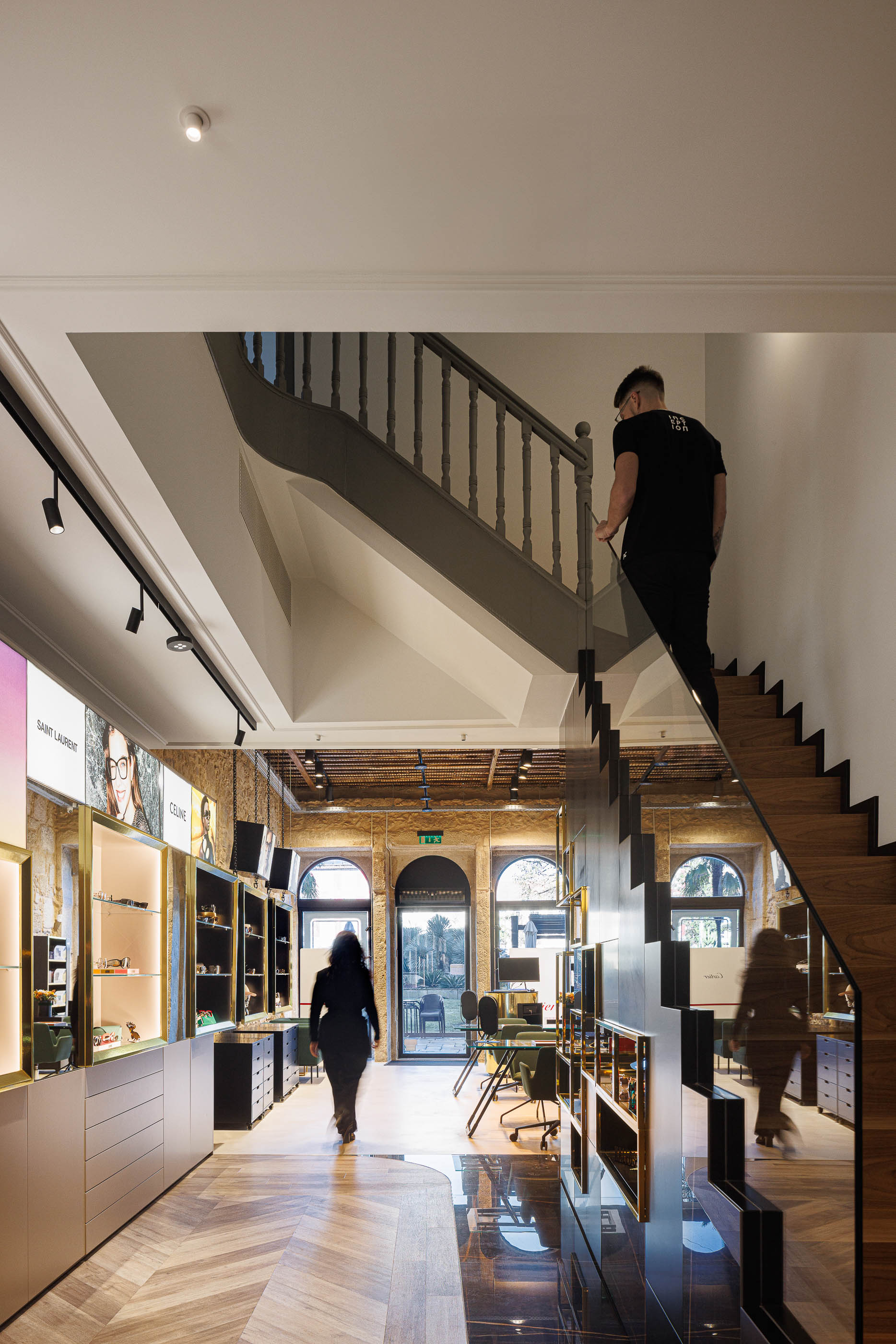 Loja: Escadas de acesso ao piso superior, expositores de óculos e pavimento em espinha de peixe. — Jorge Oculista arquitetura Inception Architects Studio em Braga