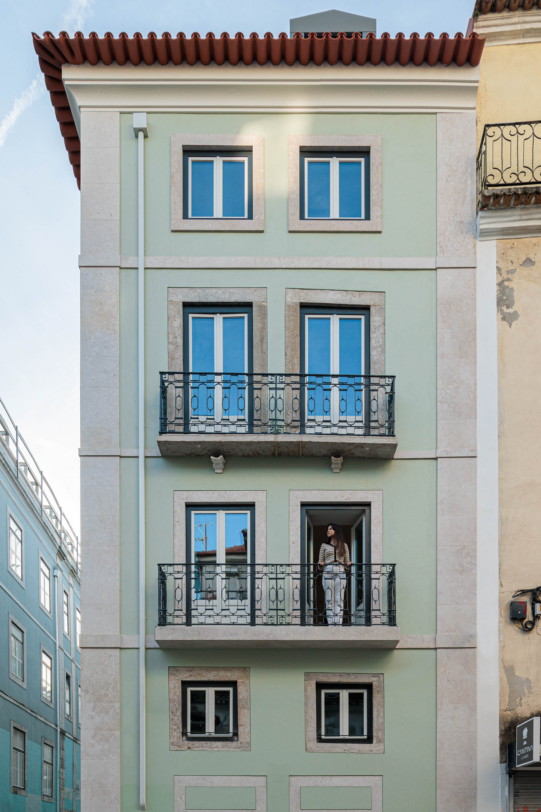 Fachada: Edifício reabilitado com fachada verde-água, caixilharia cinza e varandas em ferro forjado. — Anjos 25 arquitetura Pedro Carrilho Arquitectos em Lisboa