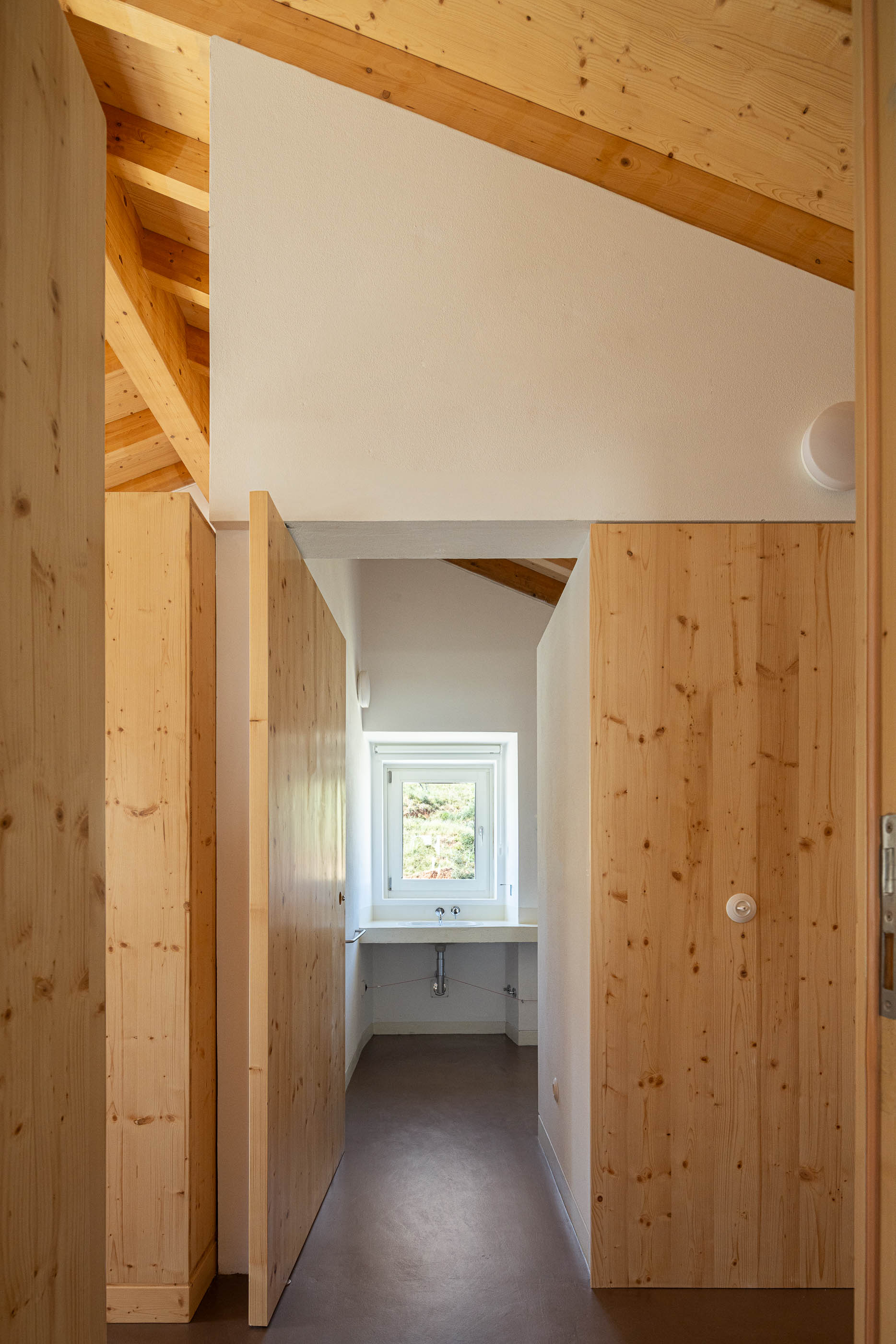Armazém: Corredor com armários de madeira e teto de madeira, com lavatório ao fundo. — Olaria Municipal arquitetura ARDE Arquitetura+Design em Odemira