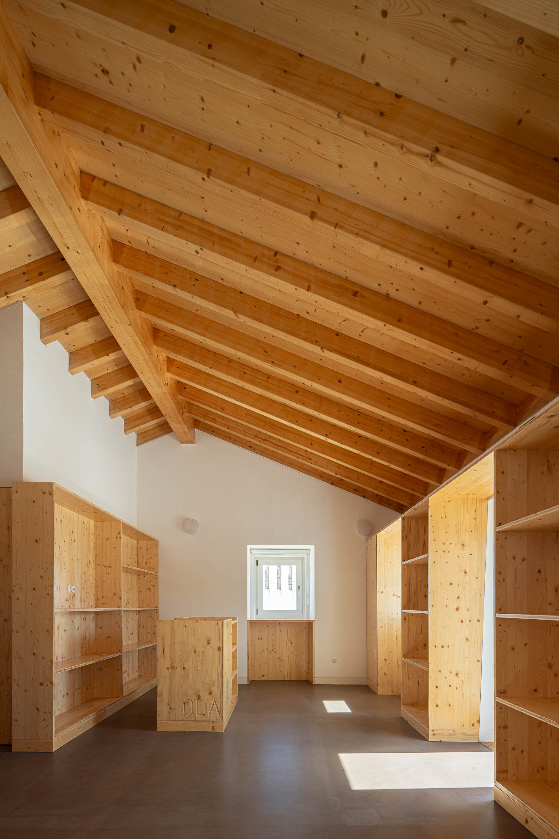 Armazém: Sala com teto de madeira, armários de madeira e pavimento castanho. — Olaria Municipal arquitetura ARDE Arquitetura+Design em Odemira