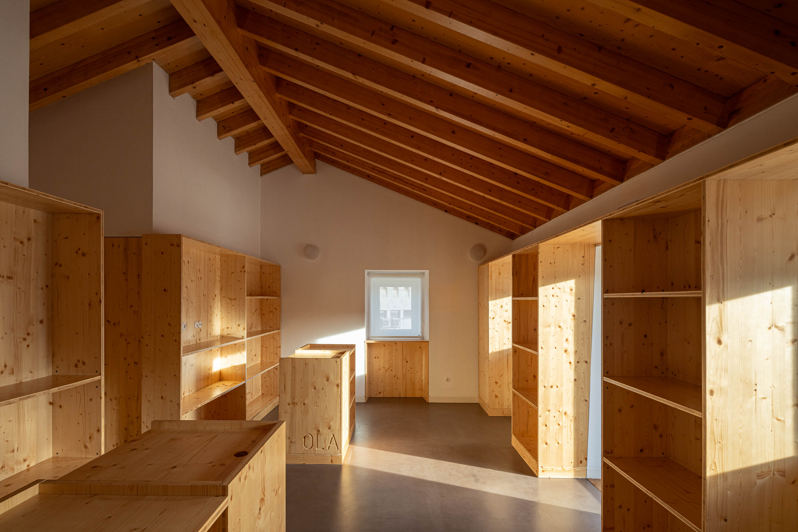 Armazém: Sala com teto de madeira, armários de madeira e pavimento castanho. — Olaria Municipal arquitetura ARDE Arquitetura+Design em Odemira
