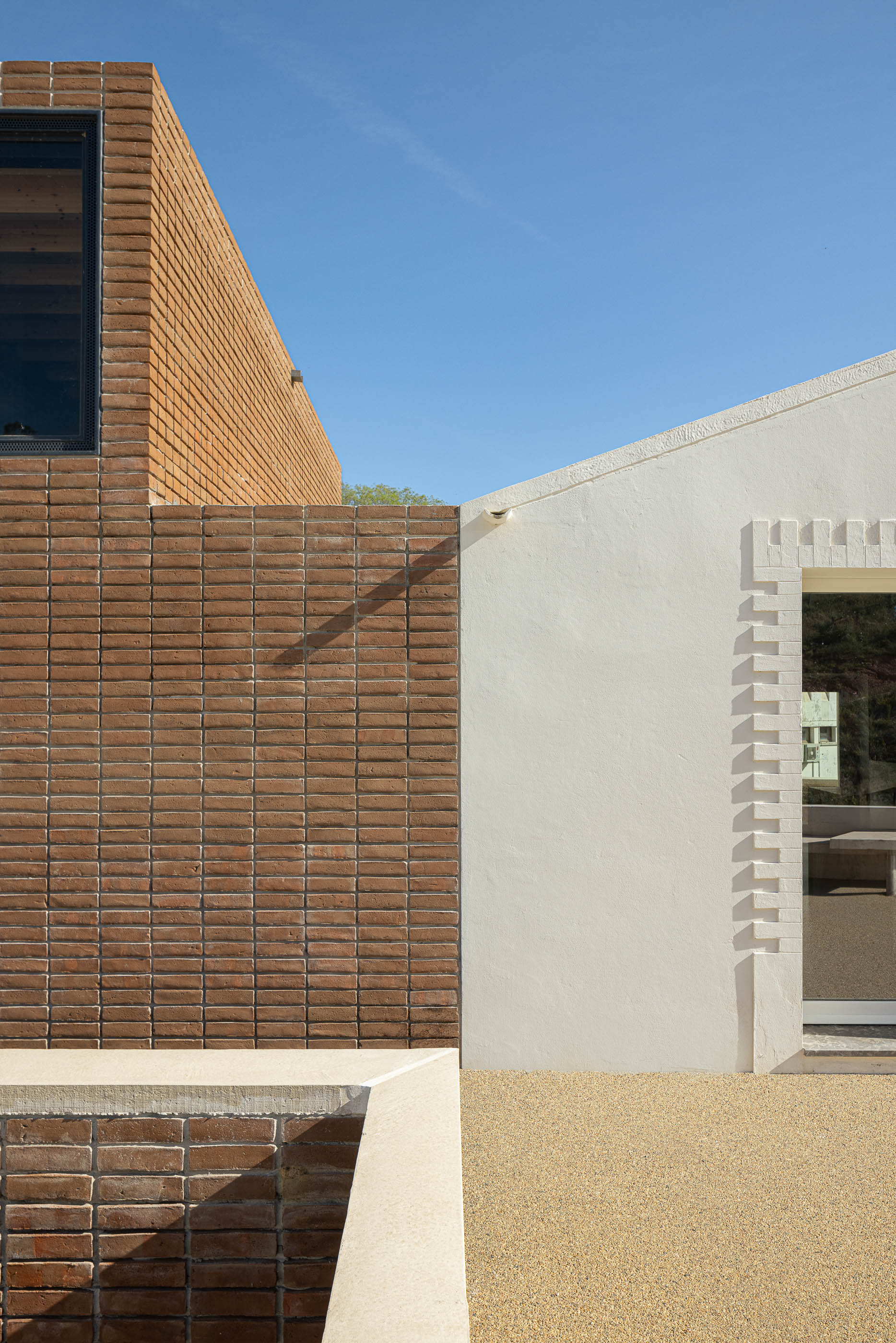 Fachada: Detalhe da junção entre a parede branca e a torre de tijolo. — Olaria Municipal arquitetura ARDE Arquitetura+Design em Odemira