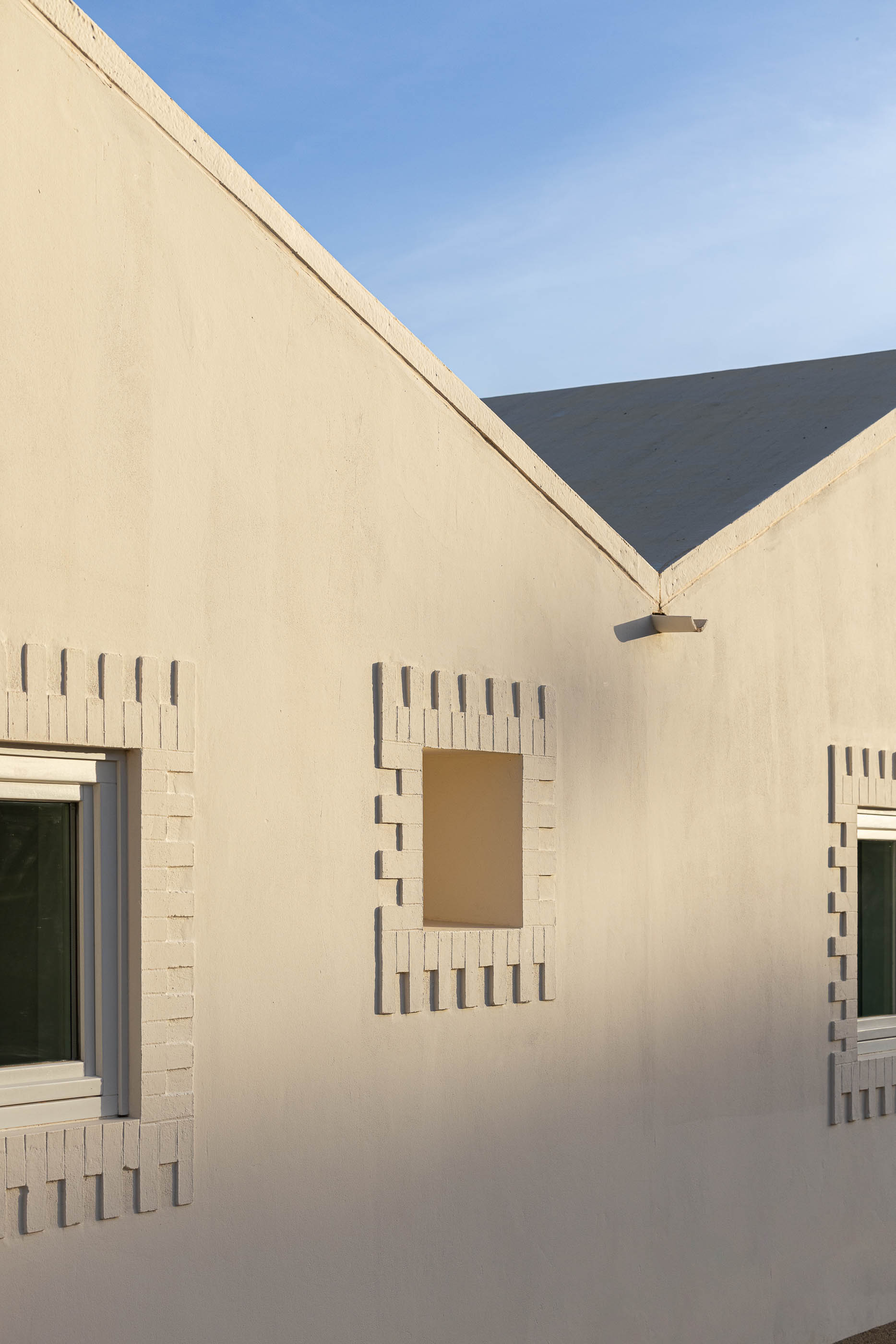 Fachada: Detalhe da parede branca com janelas e detalhes em tijolo. — Olaria Municipal arquitetura ARDE Arquitetura+Design em Odemira