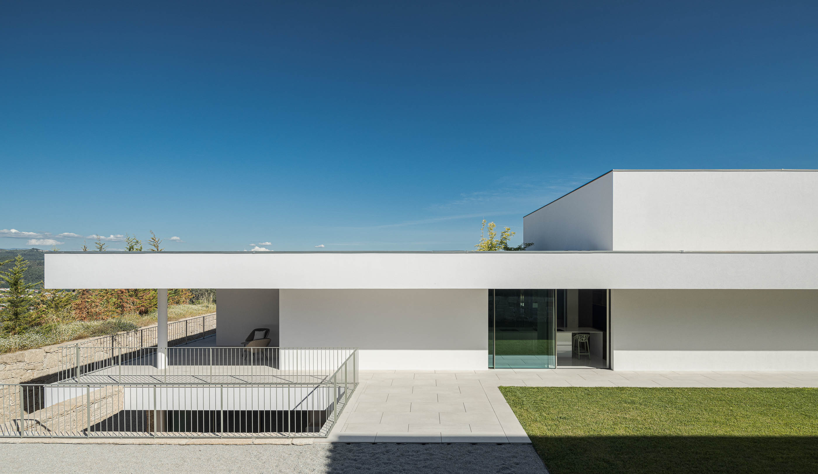 Vista exterior da moradia com relvado, terraço e escadas de acesso. — Habitação Áurea arquitetura stu.dere em Amarante