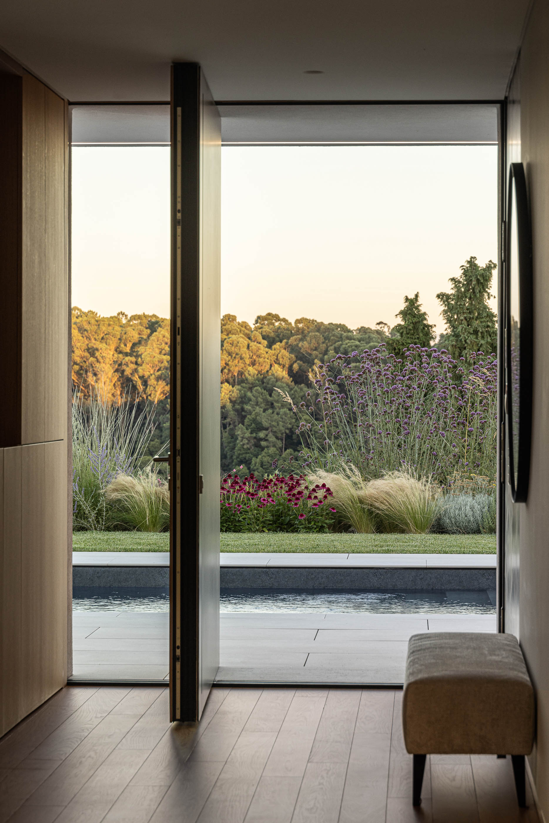 Corredor com pavimento de madeira e vista para o exterior com piscina. — Habitação Áurea arquitetura stu.dere em Amarante