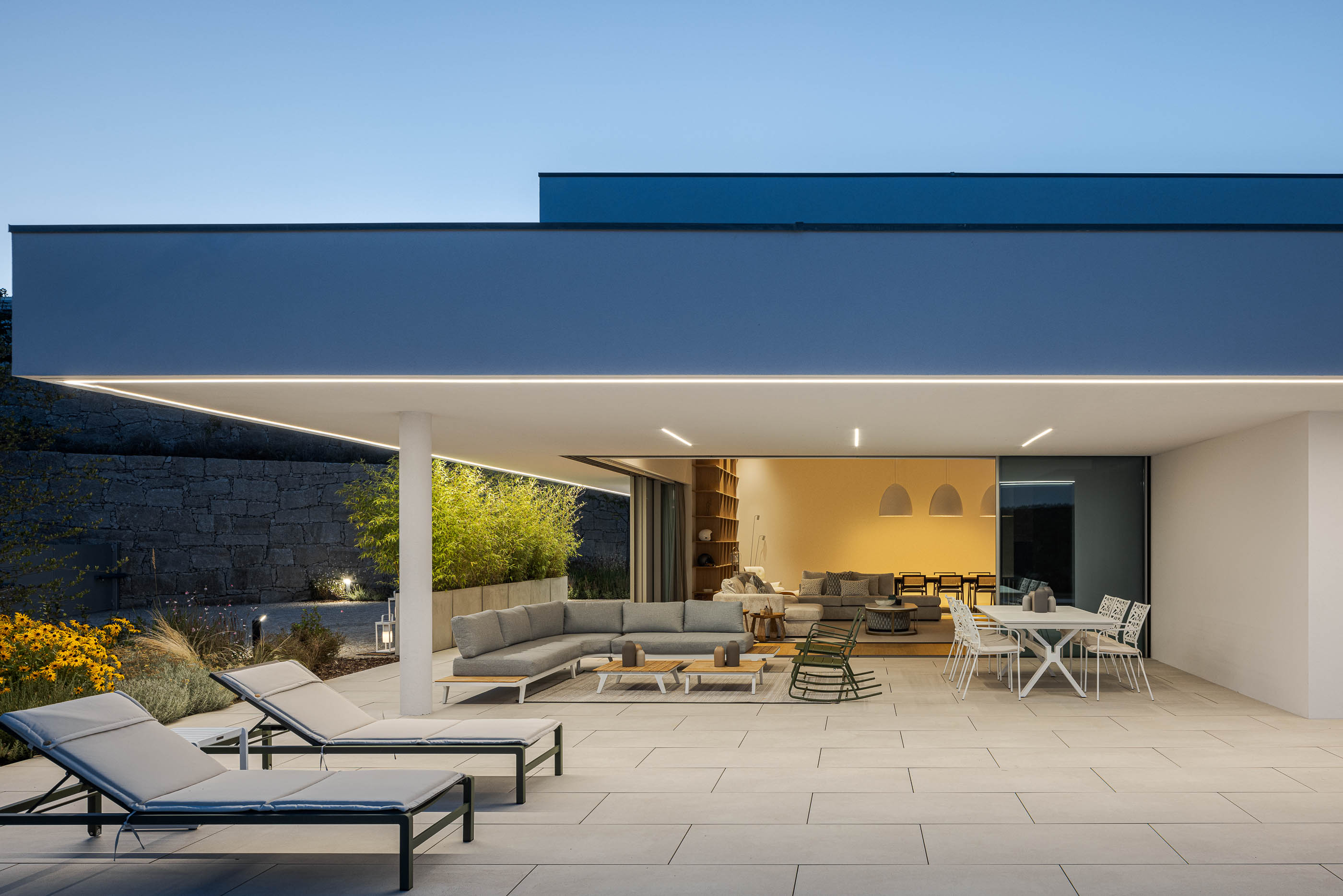 Terraço coberto com mobiliário de exterior, piscina e vista para a sala de estar. — Habitação Áurea arquitetura stu.dere em Amarante
