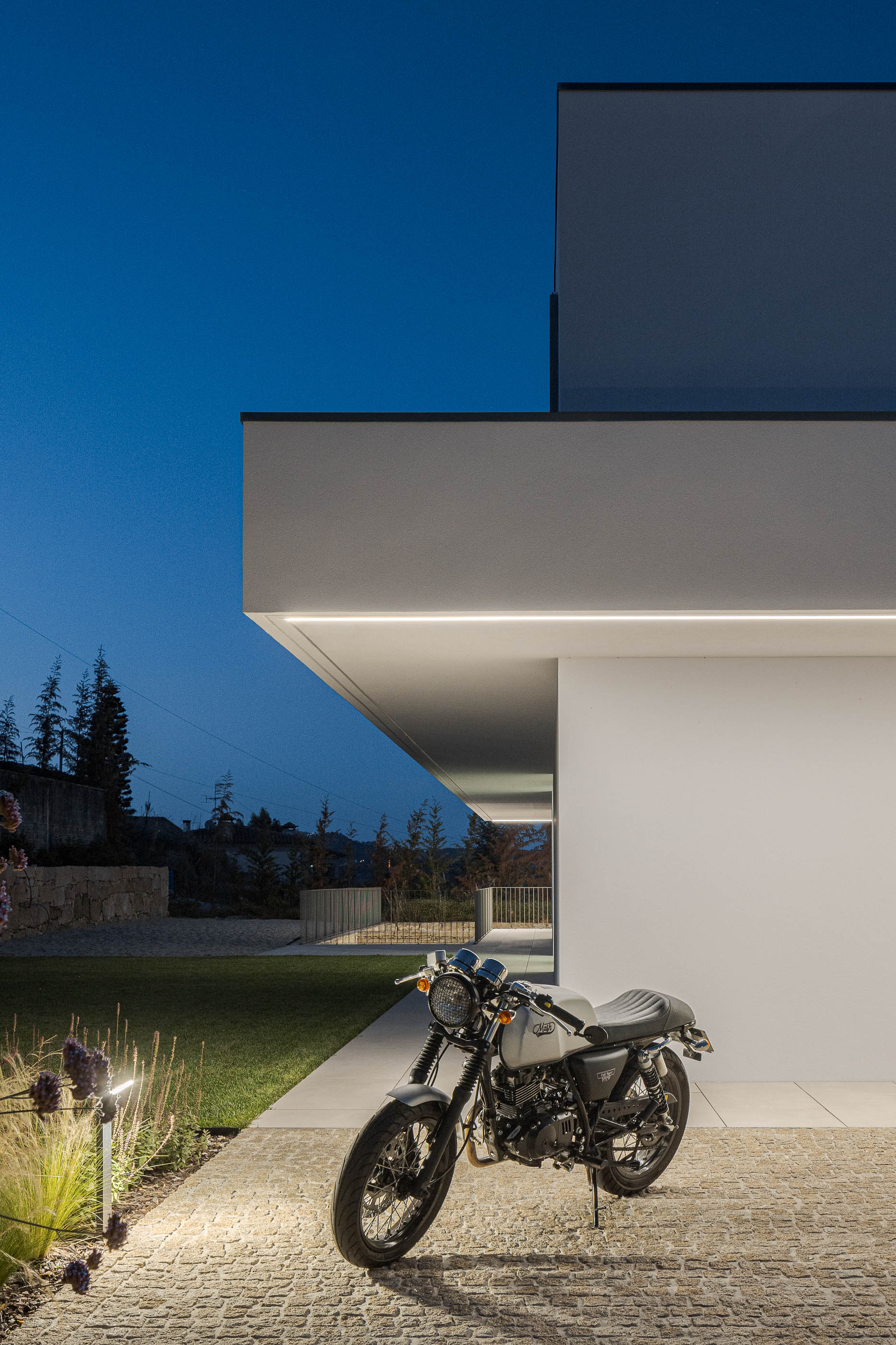 Exterior da moradia com mota estacionada e iluminação exterior. — Habitação Áurea arquitetura stu.dere em Amarante