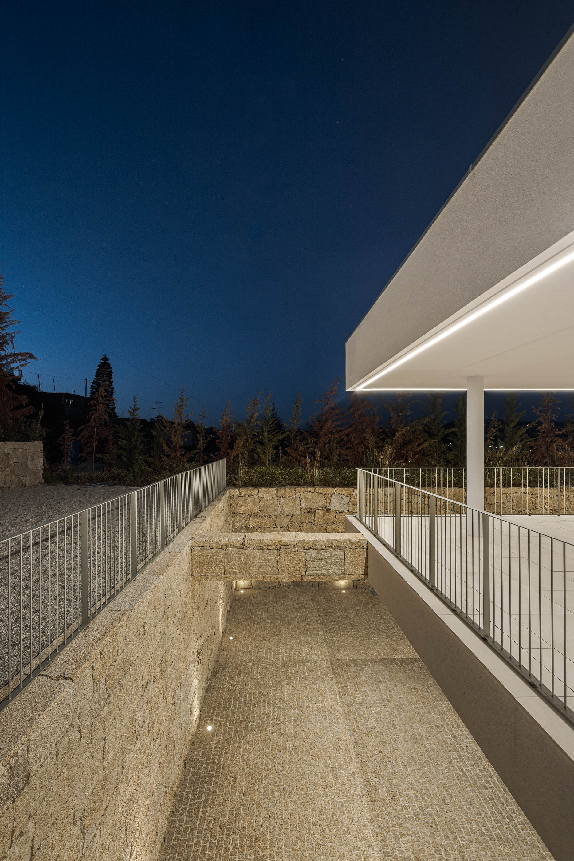 Acesso à moradia com escadas em pedra e iluminação embutida. — Habitação Áurea arquitetura stu.dere em Amarante
