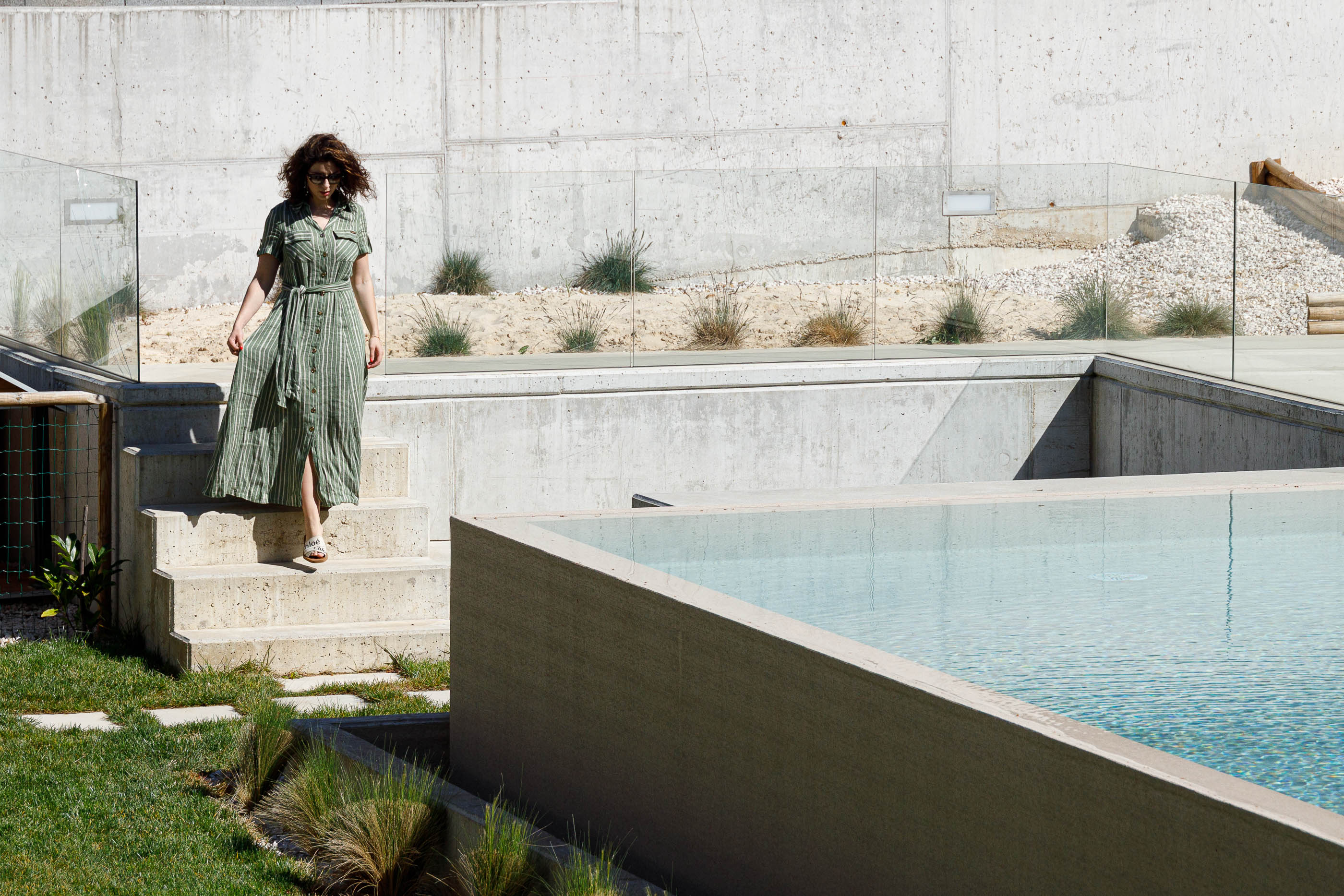 Exterior: Piscina com mulher a descer as escadas e parede de betão ao fundo. — Casa em Mundão arquitetura Um para Um, arquitectura e engenharia em Viseu