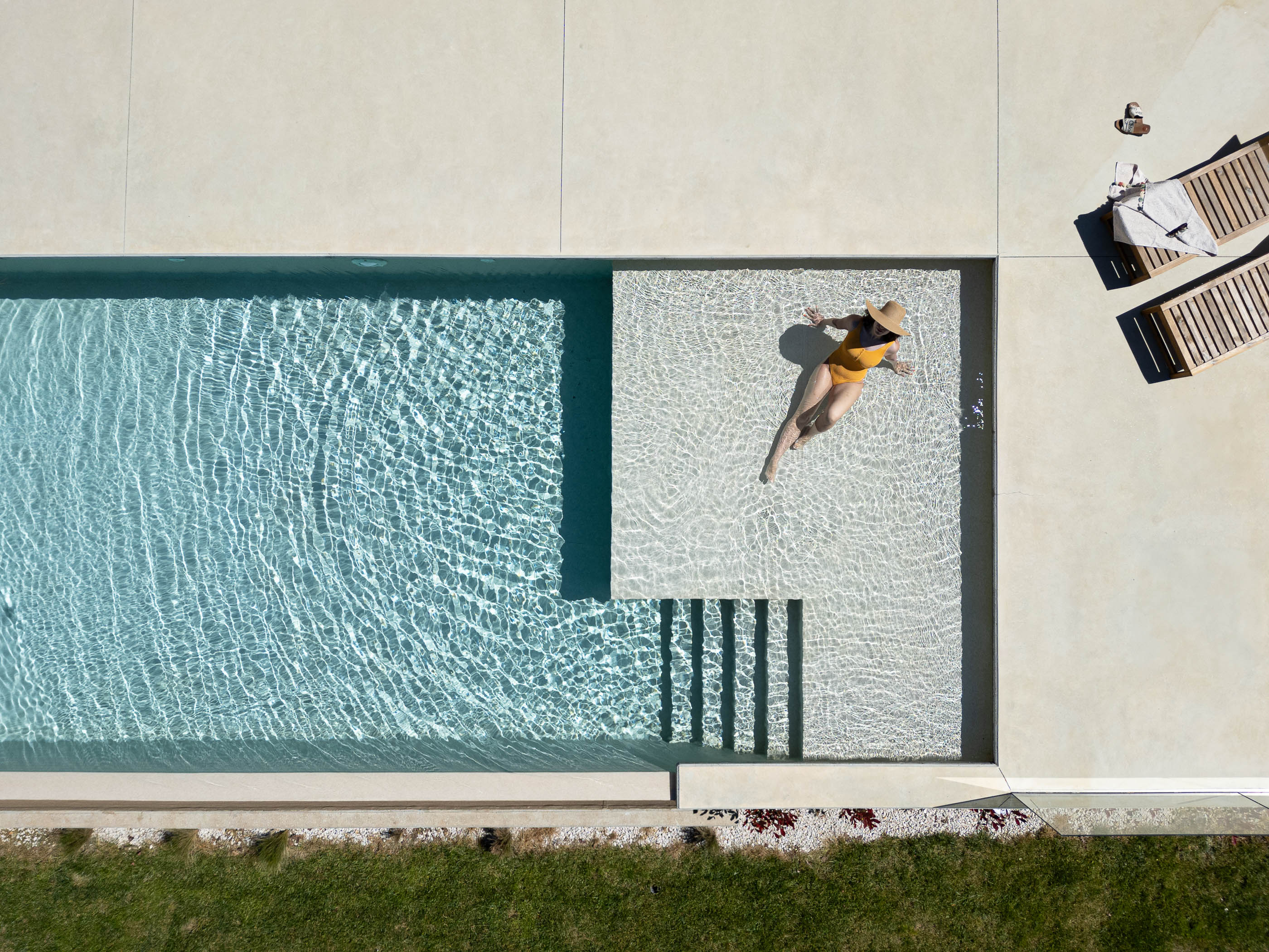 Exterior: Vista aérea da piscina com mulher a relaxar, espreguiçadeiras e relvado. — Casa em Mundão arquitetura Um para Um, arquitectura e engenharia em Viseu