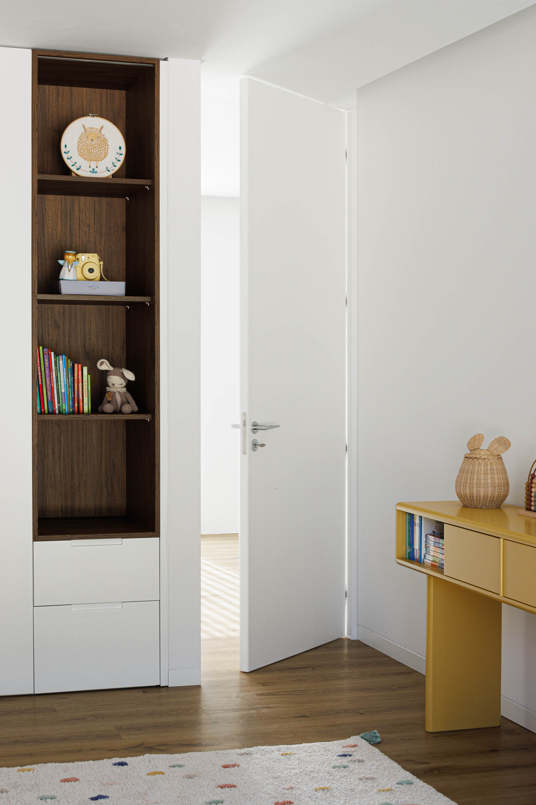 Quarto infantil: Estante com brinquedos, secretária amarela e alcatifa colorida. — Casa em Mundão arquitetura Um para Um, arquitectura e engenharia em Viseu